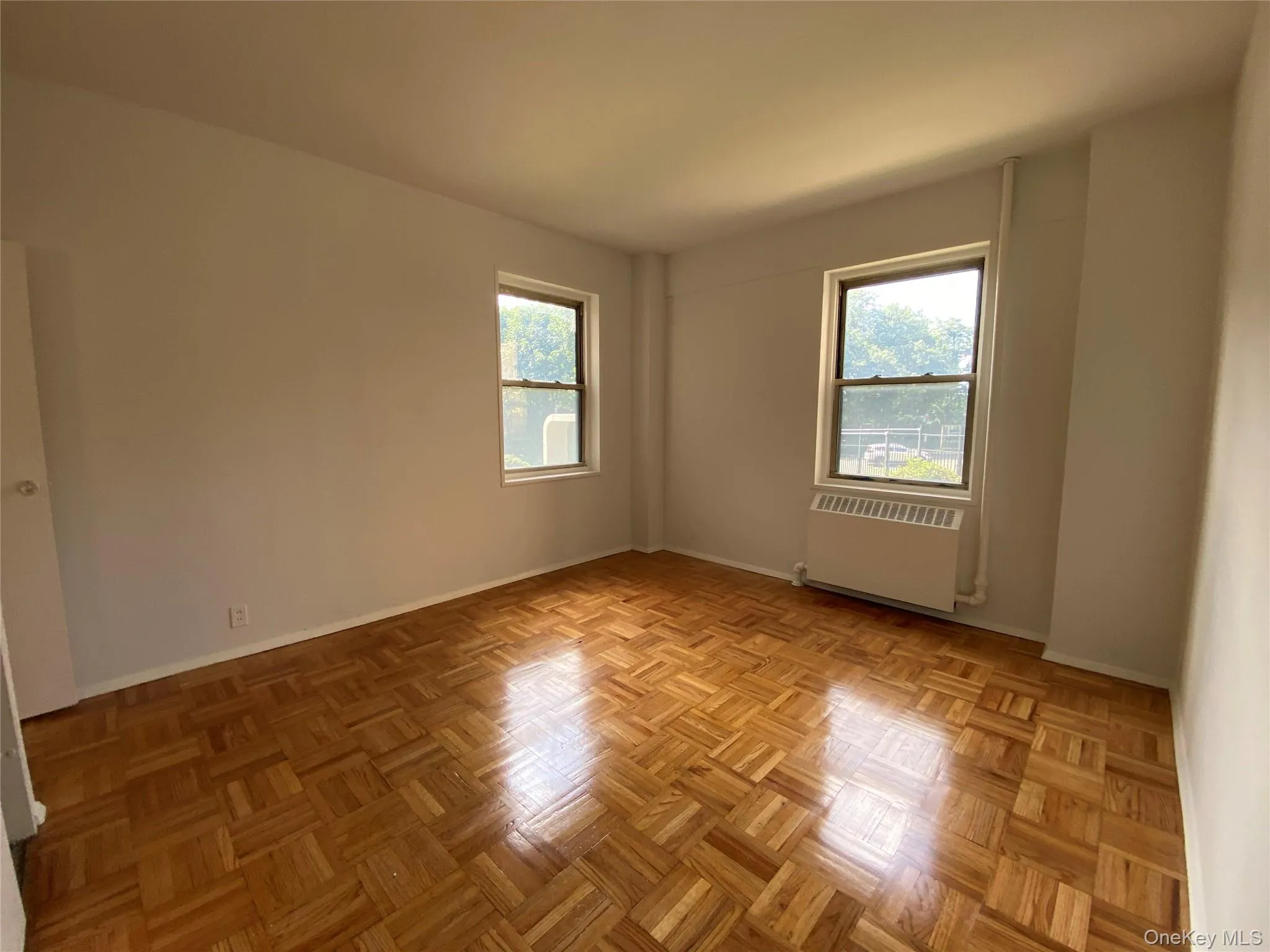 Unfurnished room featuring radiator heating unit and plenty of natural light Unfurnished room featuring radiator heating unit and plenty of natural light
