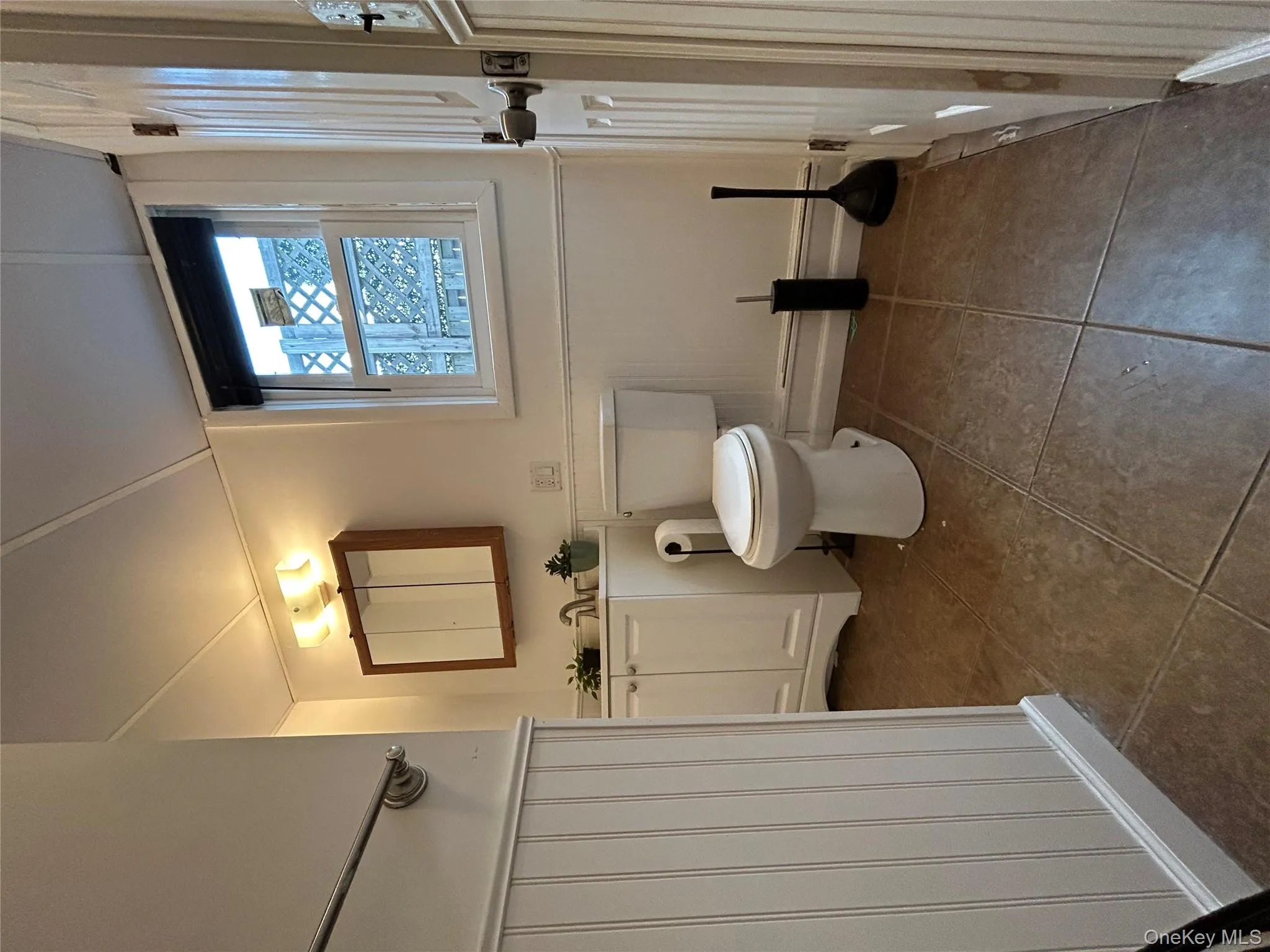 Bathroom with wainscoting, vanity, a decorative wall, and dark tile patterned floors Bathroom with wainscoting, vanity, a decorative wall, and dark tile patterned floors