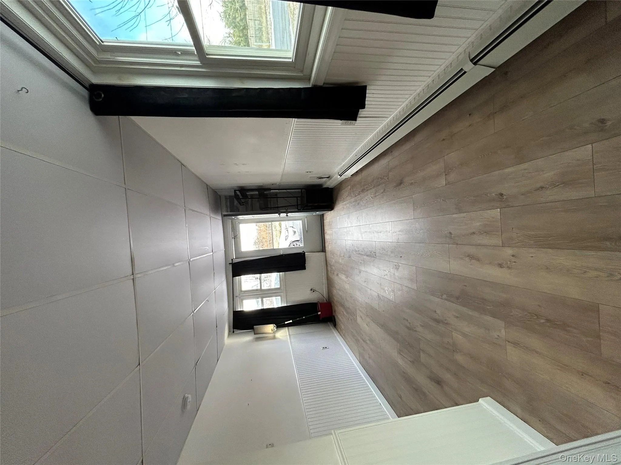 Spare room with baseboard heating, wainscoting, a drop ceiling, and hardwood / wood-style floors Spare room with baseboard heating, wainscoting, a drop ceiling, and hardwood / wood-style floors