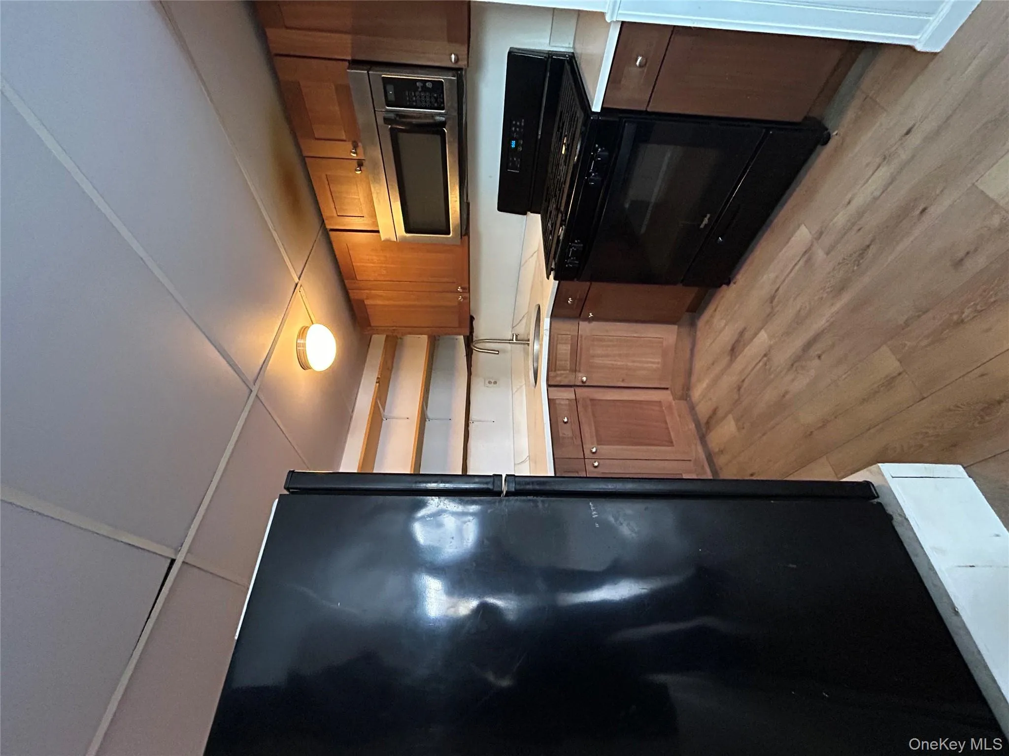 Kitchen with open shelves, black appliances, brown cabinets, and light countertops Kitchen with open shelves, black appliances, brown cabinets, and light countertops