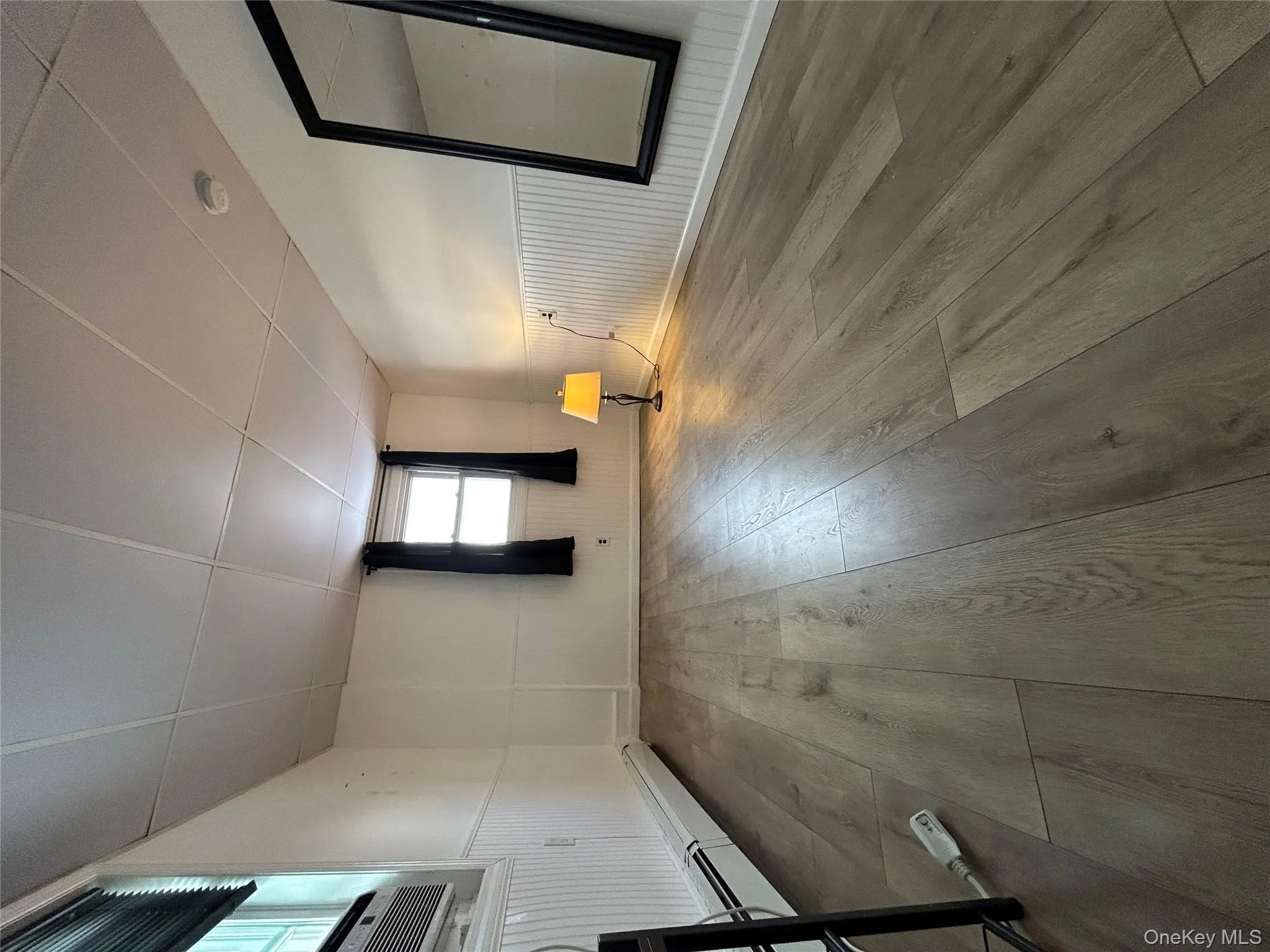 Unfurnished room with wainscoting, a paneled ceiling, a baseboard radiator, and wood-type flooring Unfurnished room with wainscoting, a paneled ceiling, a baseboard radiator, and wood-type flooring