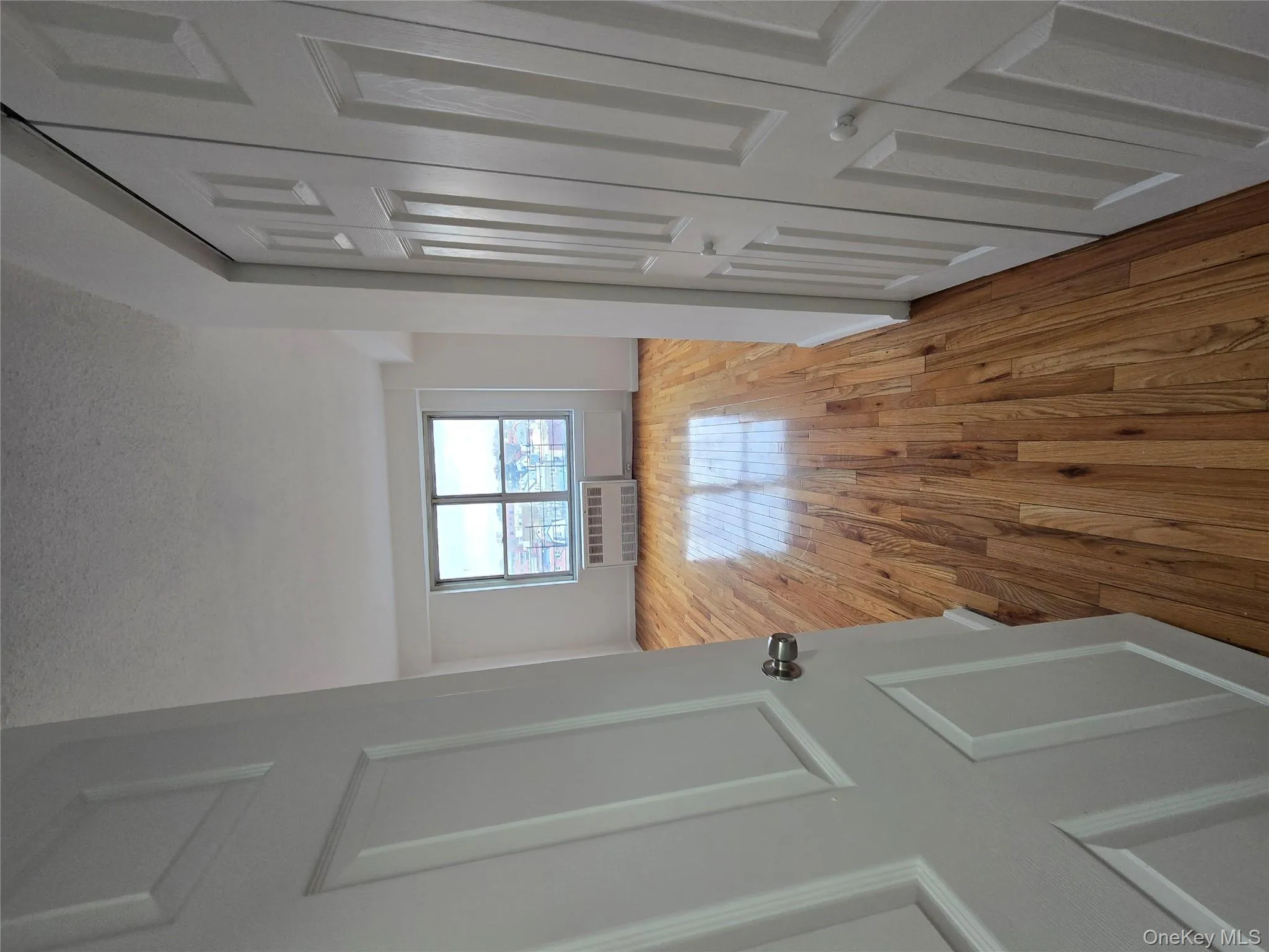Hallway with light wood-type flooring, a textured ceiling, and radiator heating unit Hallway with light wood-type flooring, a textured ceiling, and radiator heating unit