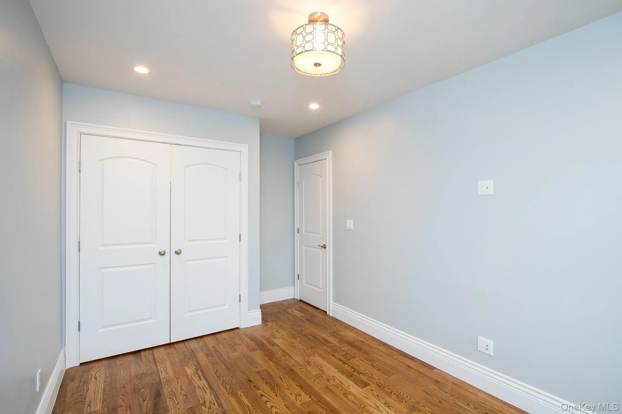Unfurnished bedroom with wood finished floors, a closet, and recessed lighting Unfurnished bedroom with wood finished floors, a closet, and recessed lighting