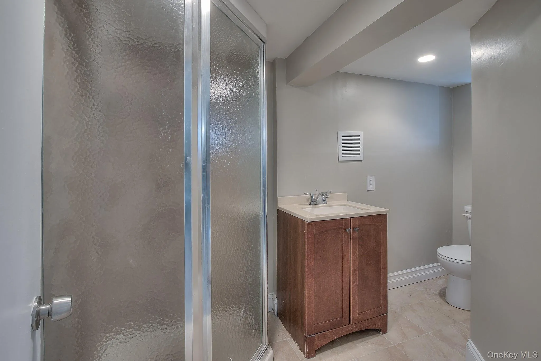 Bathroom with a stall shower, vanity, light tile patterned flooring, and recessed lighting Bathroom with a stall shower, vanity, light tile patterned flooring, and recessed lighting