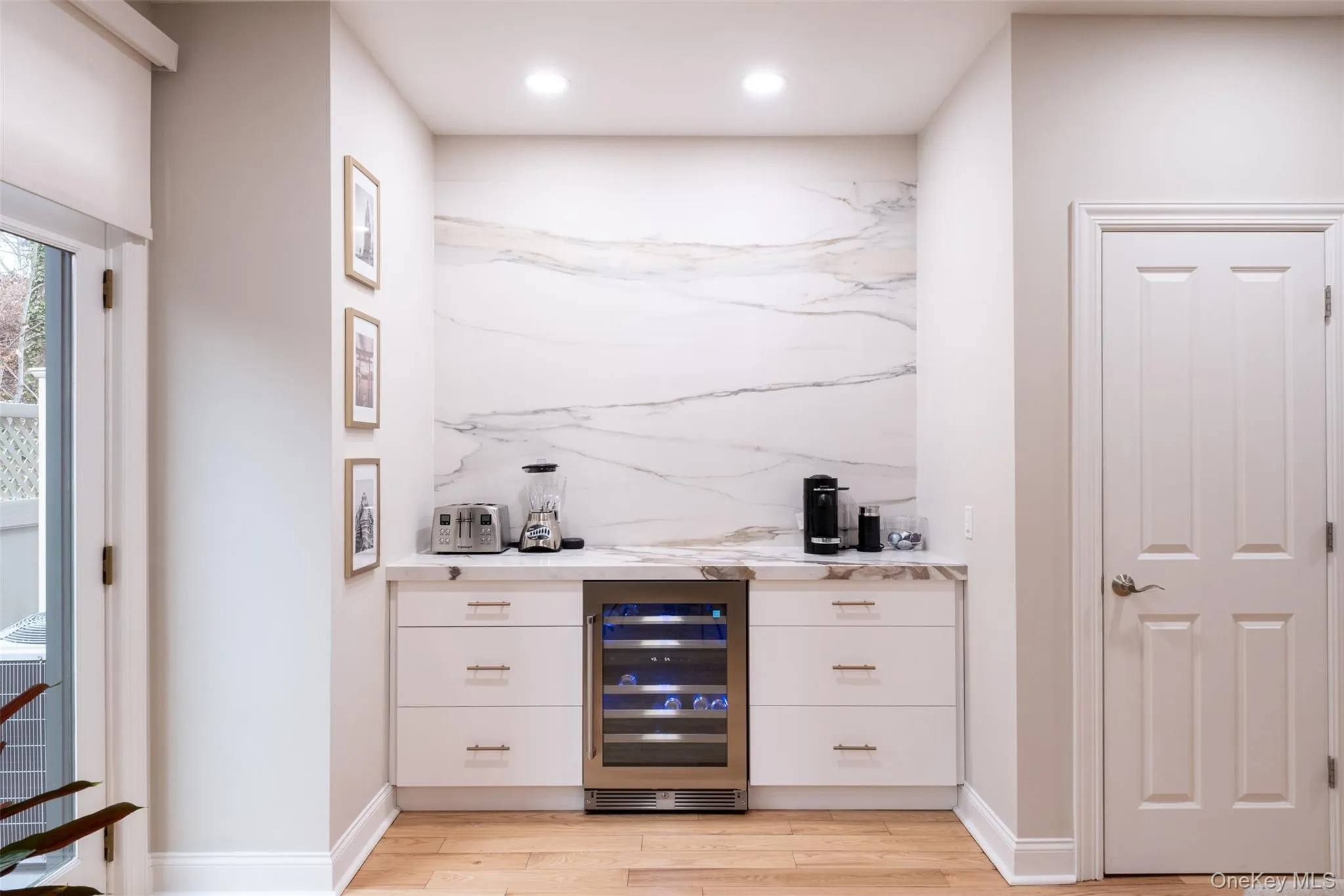 Indoor dry bar with white cabinetry, beverage cooler, light stone counters, light wood-style floors, and recessed lighting Indoor dry bar with white cabinetry, beverage cooler, light stone counters, light wood-style floors, and recessed lighting