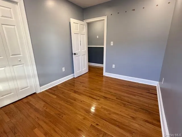 Unfurnished bedroom with dark wood-style floors and a closet Unfurnished bedroom with dark wood-style floors and a closet