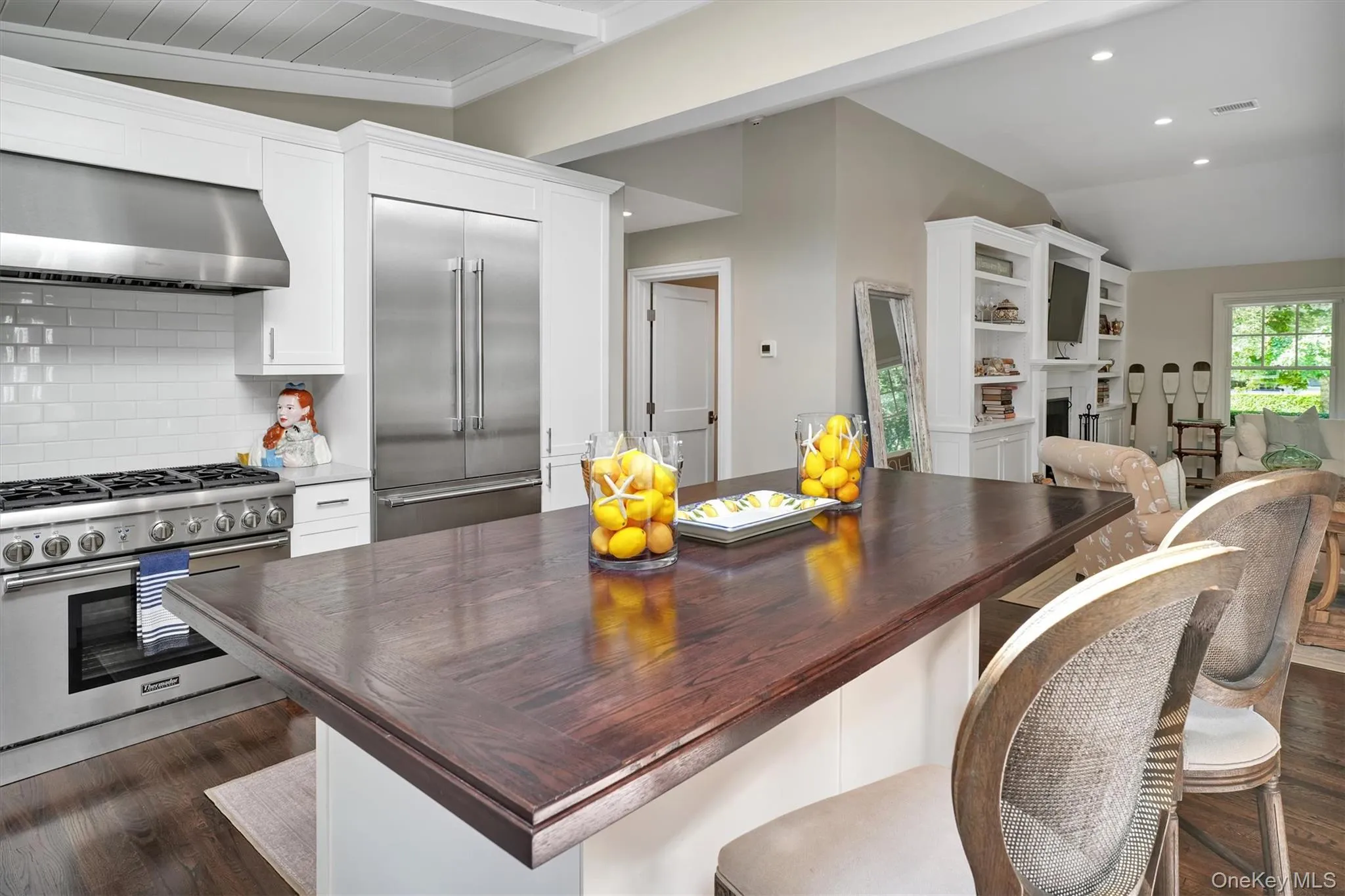 Kitchen featuring white cabinetry, premium appliances, under cabinet range hood, a kitchen bar, and recessed lighting Kitchen featuring white cabinetry, premium appliances, under cabinet range hood, a kitchen bar, and recessed lighting