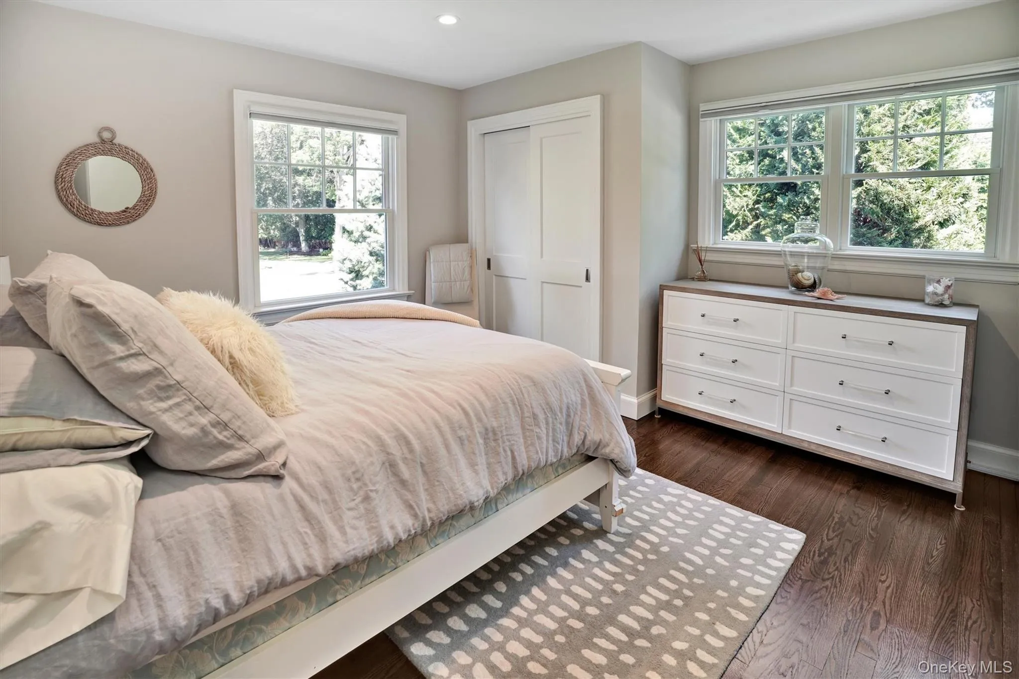 Bedroom featuring multiple windows, dark wood-style flooring, and a closet Bedroom featuring multiple windows, dark wood-style flooring, and a closet