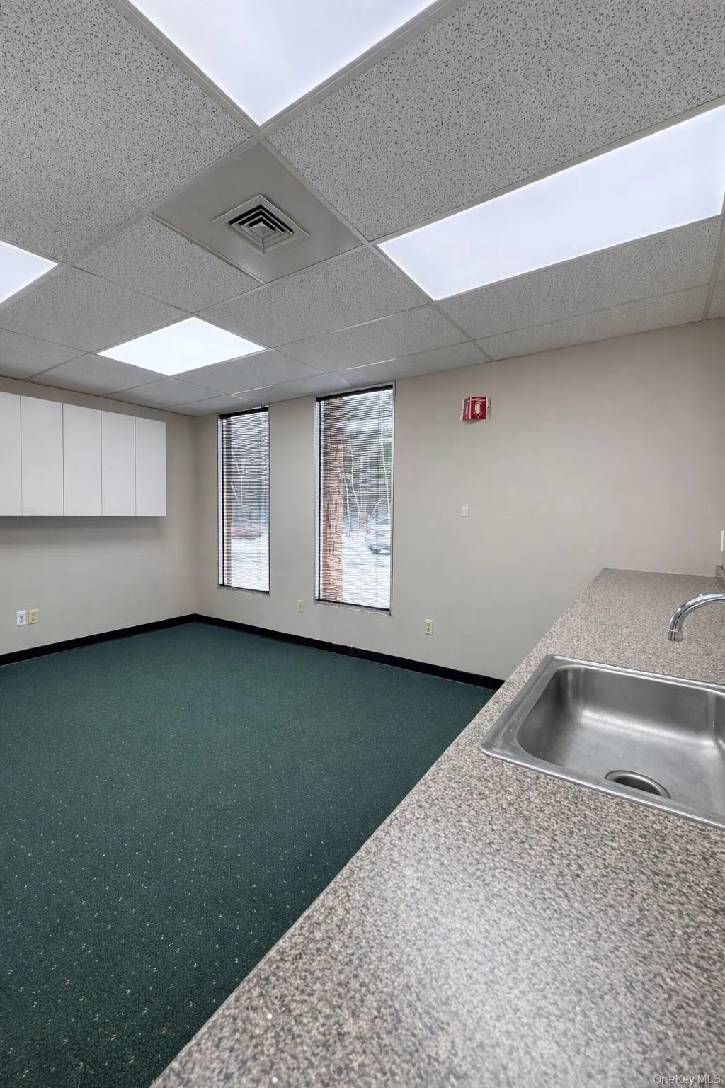 Kitchen featuring a drop ceiling, white cabinets, and open floor plan Kitchen featuring a drop ceiling, white cabinets, and open floor plan