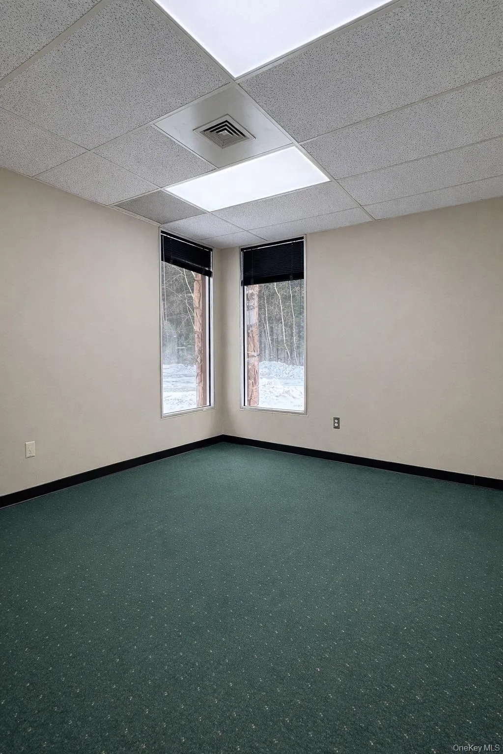 Empty room with a drop ceiling and carpet flooring Empty room with a drop ceiling and carpet flooring