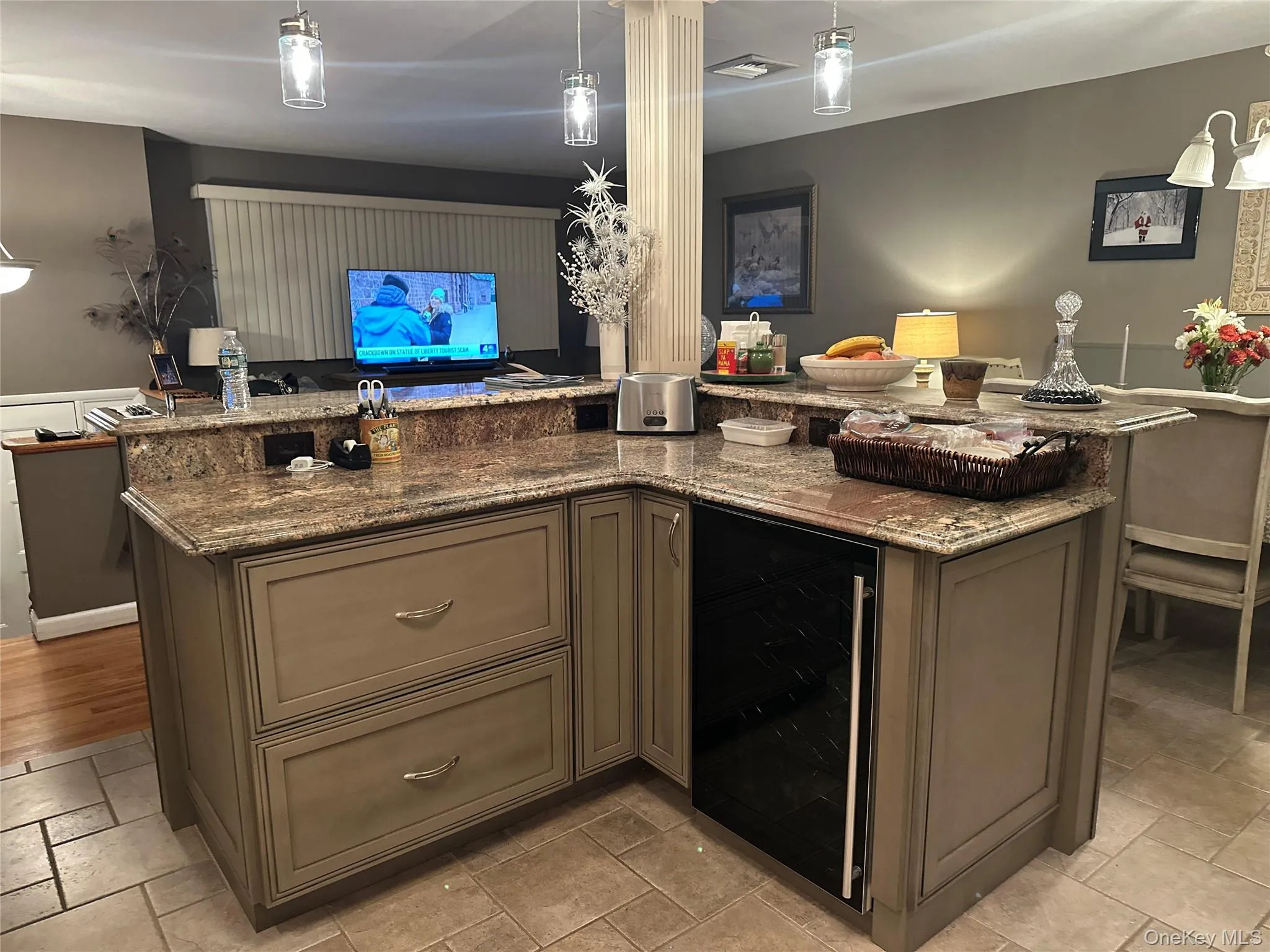 Kitchen with hanging light fixtures, dark stone countertops, open floor plan, and beverage cooler Kitchen with hanging light fixtures, dark stone countertops, open floor plan, and beverage cooler