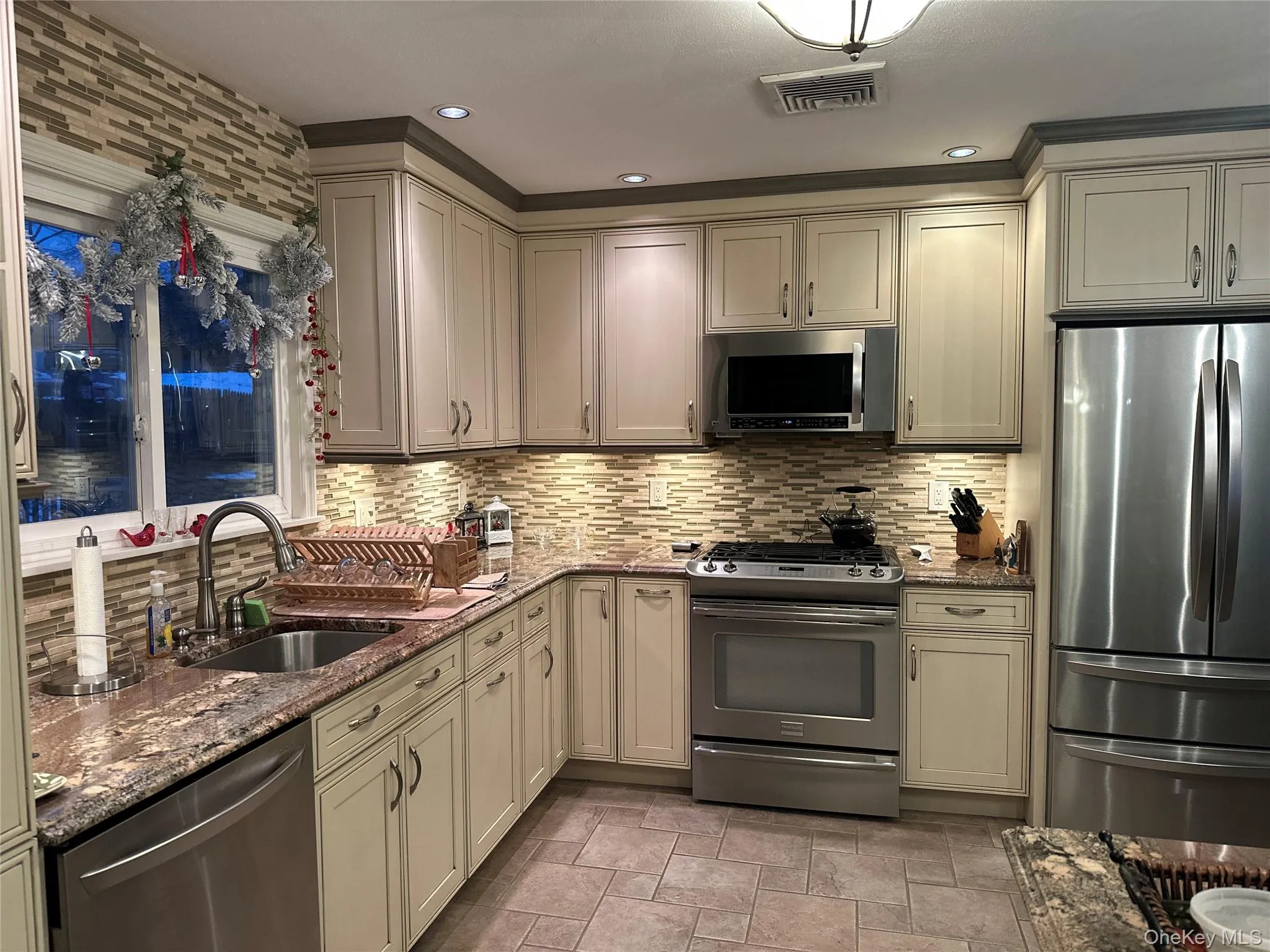 Kitchen featuring stainless steel appliances, dark stone counters, cream cabinetry, tasteful backsplash, and recessed lighting Kitchen featuring stainless steel appliances, dark stone counters, cream cabinetry, tasteful backsplash, and recessed lighting