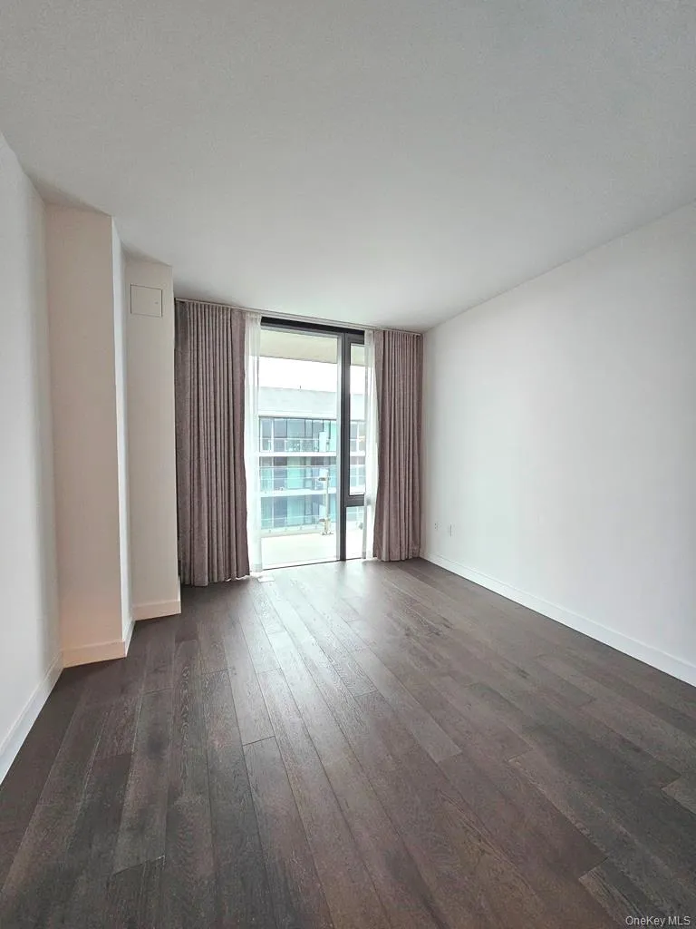 Spare room featuring floor to ceiling windows, dark wood-style floors, and a textured ceiling Spare room featuring floor to ceiling windows, dark wood-style floors, and a textured ceiling