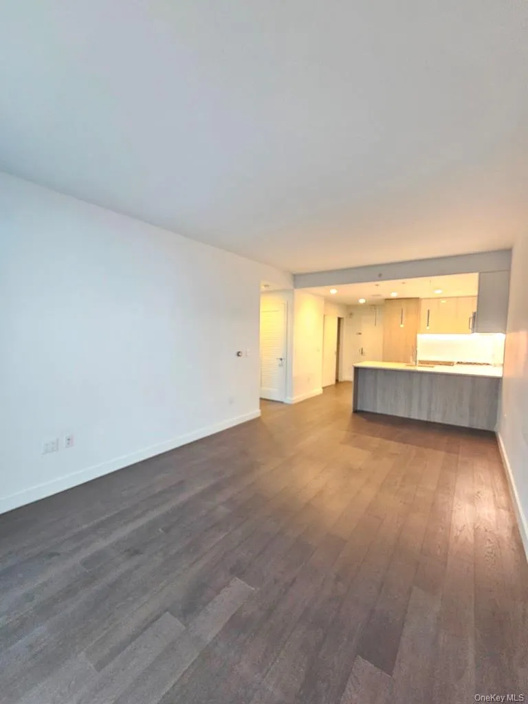 Unfurnished living room featuring baseboards and dark wood-style flooring Unfurnished living room featuring baseboards and dark wood-style flooring