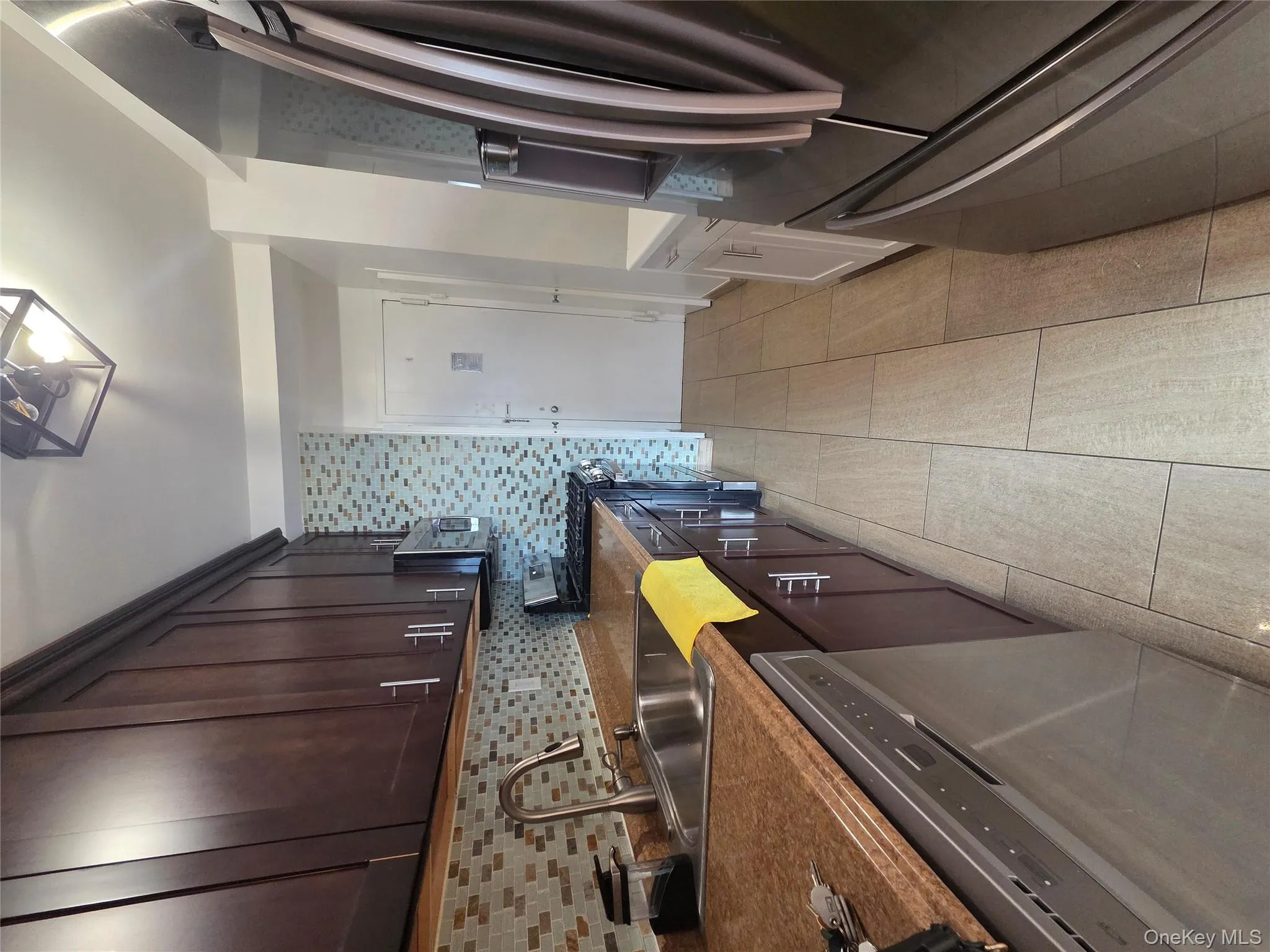 Kitchen with stainless steel appliances, dark brown cabinets, light tile patterned floors, and tasteful backsplash Kitchen with stainless steel appliances, dark brown cabinets, light tile patterned floors, and tasteful backsplash