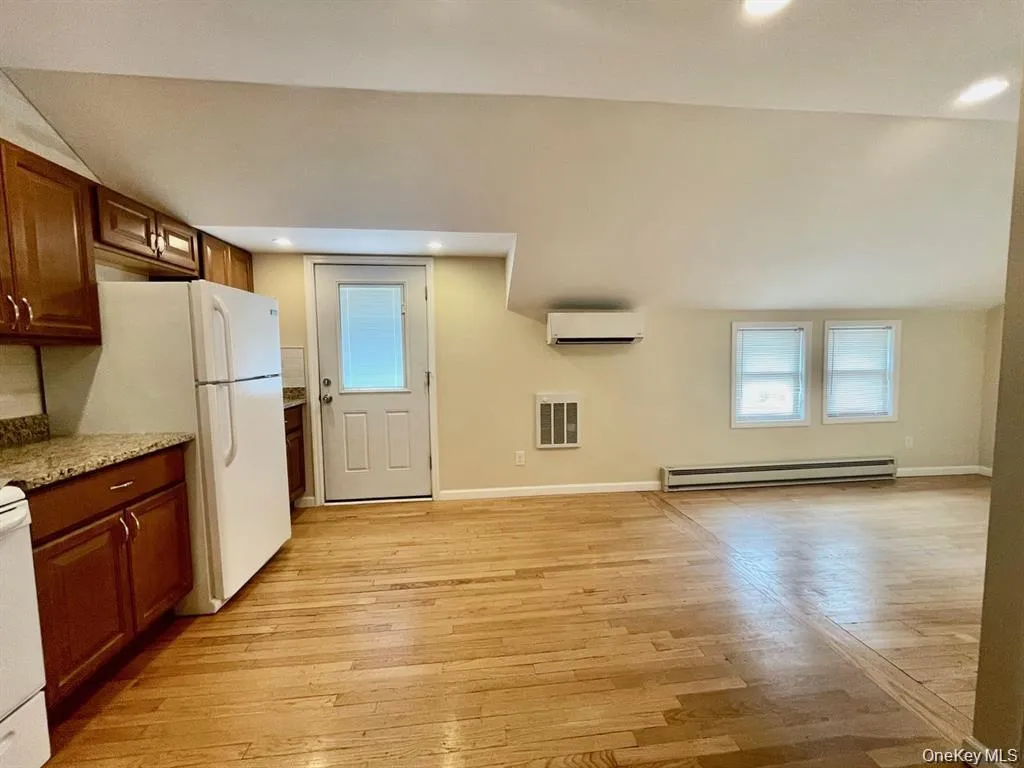 Kitchen with light wood-type flooring, baseboard heating, light stone countertops, white appliances, and recessed lighting Kitchen with light wood-type flooring, baseboard heating, light stone countertops, white appliances, and recessed lighting
