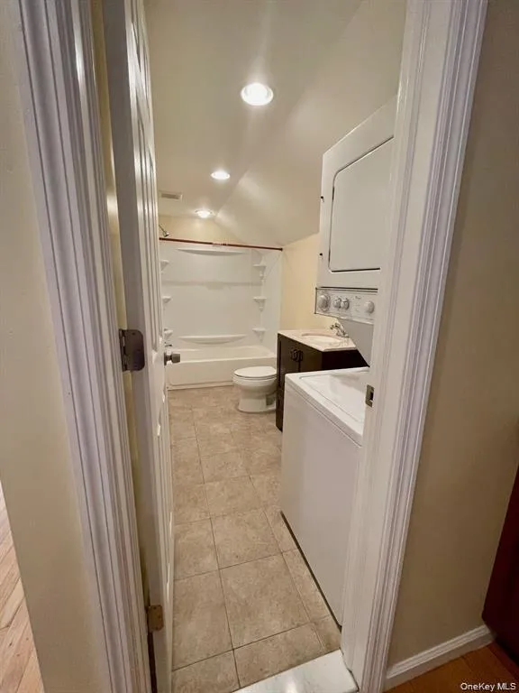 Full bath with vanity, shower combination, light tile patterned floors, recessed lighting, and stacked washer and clothes dryer Full bath with vanity, shower combination, light tile patterned floors, recessed lighting, and stacked washer and clothes dryer