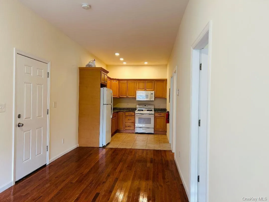 Kitchen featuring white appliances, brown cabinetry, light wood finished floors, and recessed lighting Kitchen featuring white appliances, brown cabinetry, light wood finished floors, and recessed lighting