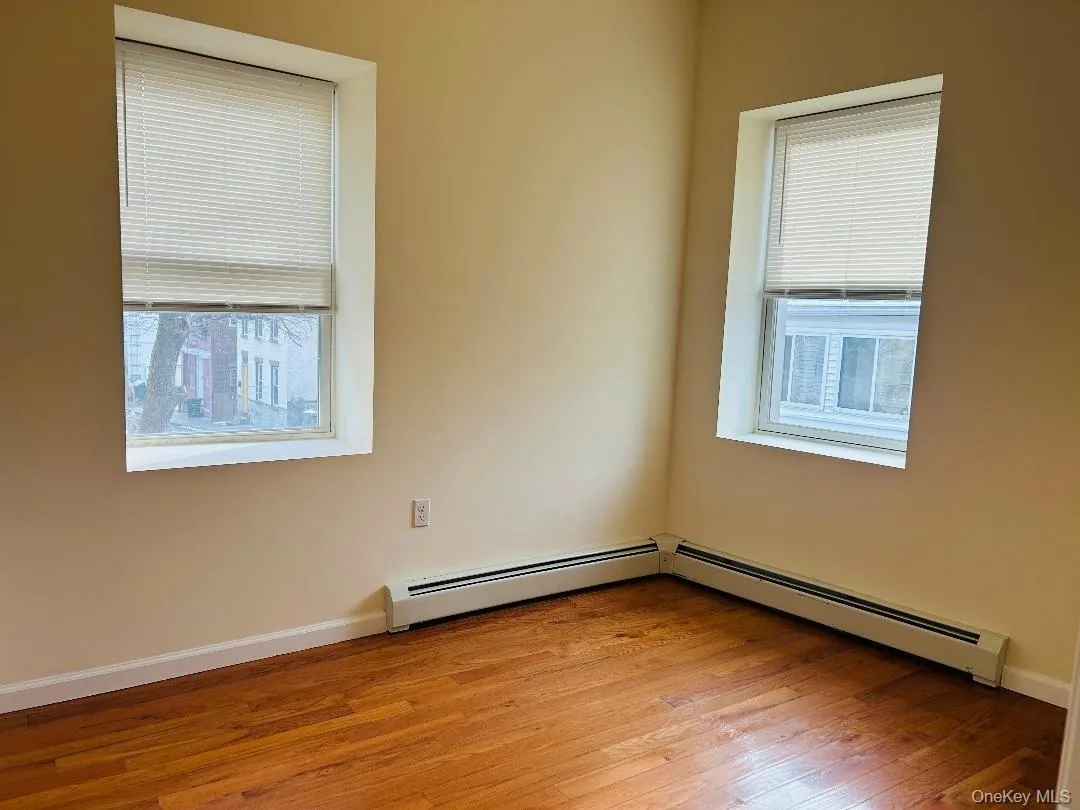 Bedroom featuring light wood finished floors and a baseboard heating unit Bedroom featuring light wood finished floors and a baseboard heating unit