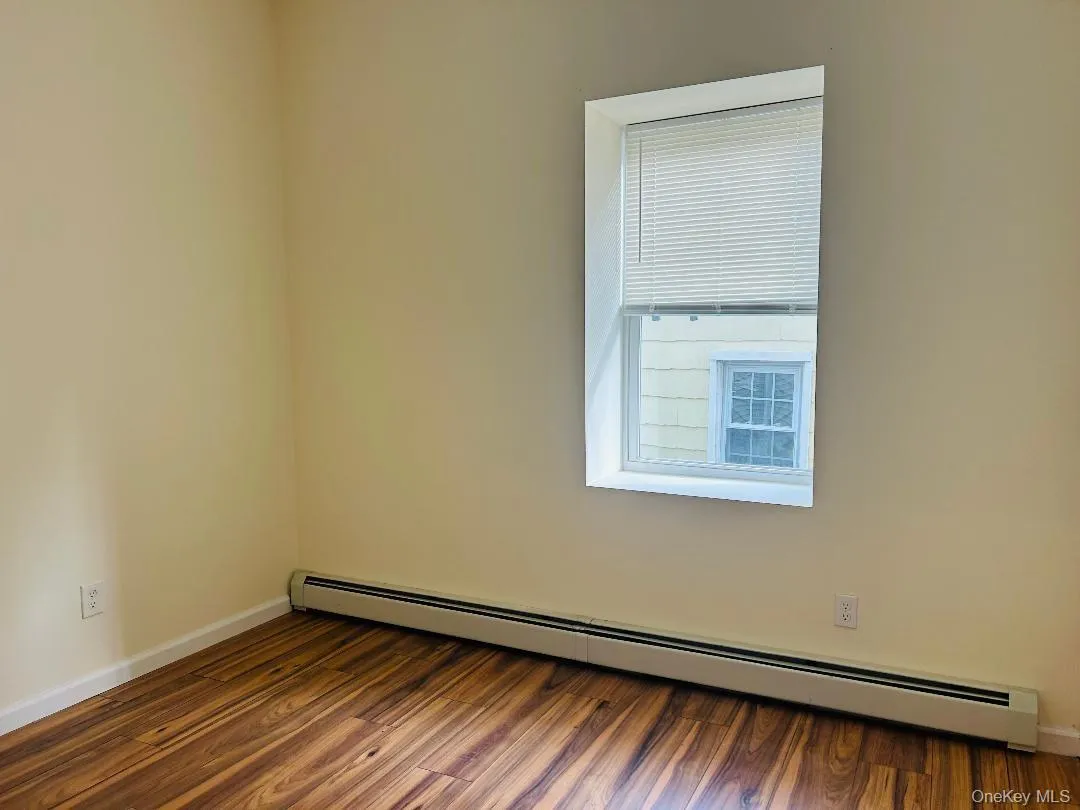 Spare room featuring a baseboard heating unit and dark wood-type flooring Spare room featuring a baseboard heating unit and dark wood-type flooring