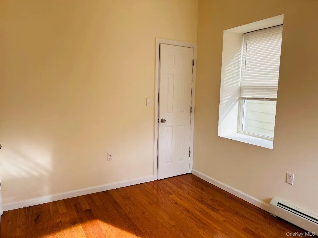 Unfurnished room with a baseboard radiator and hardwood / wood-style floors Unfurnished room with a baseboard radiator and hardwood / wood-style floors
