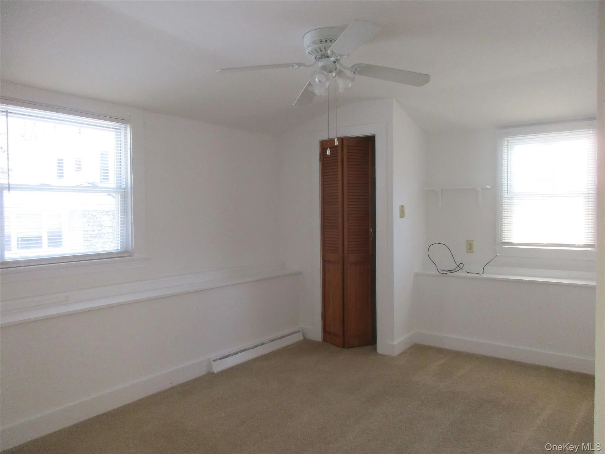 Bedroom with carpet, baseboard heating, lots of natural light, closet and ceiling fan Bedroom with carpet, baseboard heating, lots of natural light, closet and ceiling fan