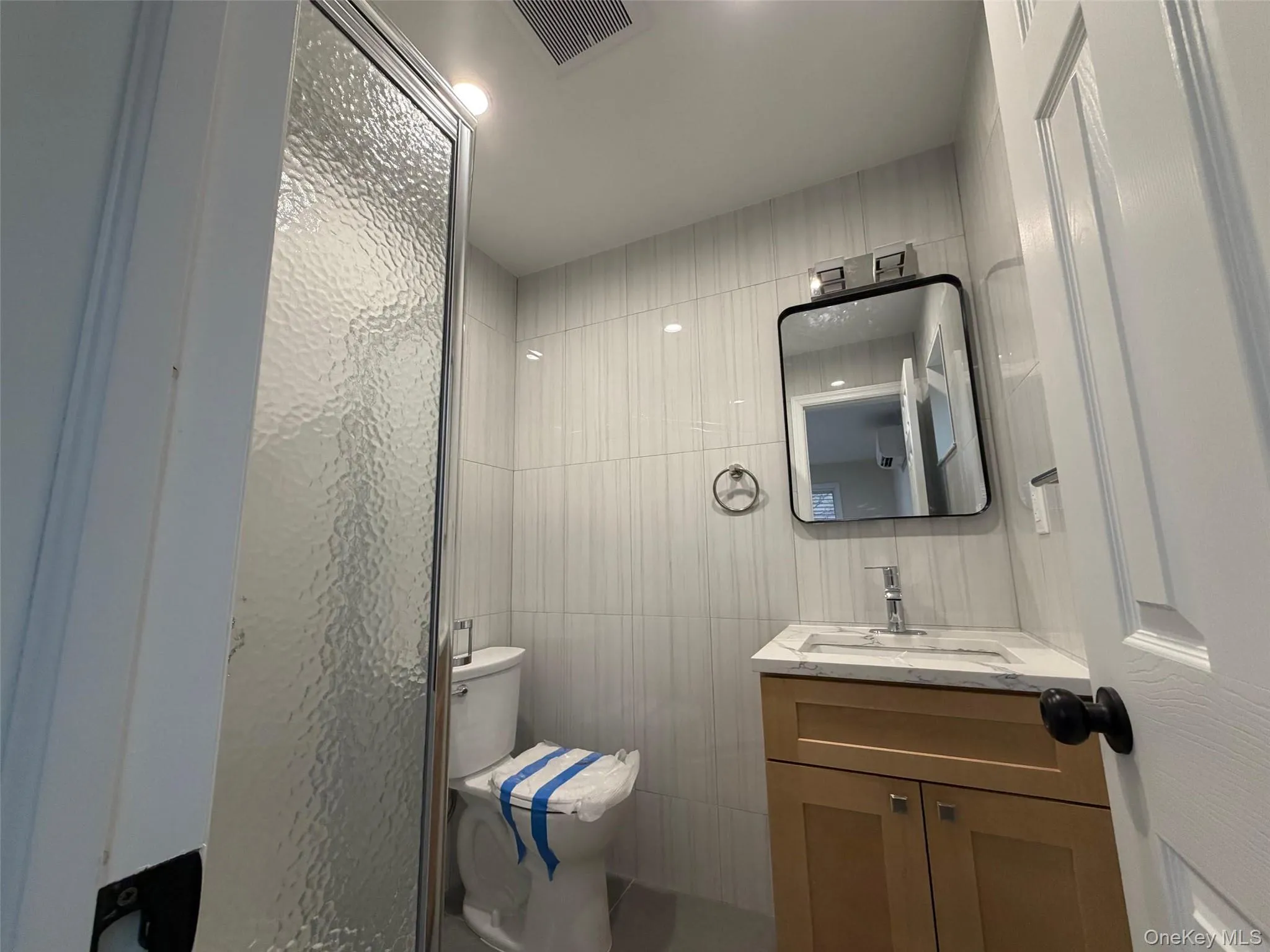 Full bath featuring vanity, a stall shower, and tile walls Full bath featuring vanity, a stall shower, and tile walls