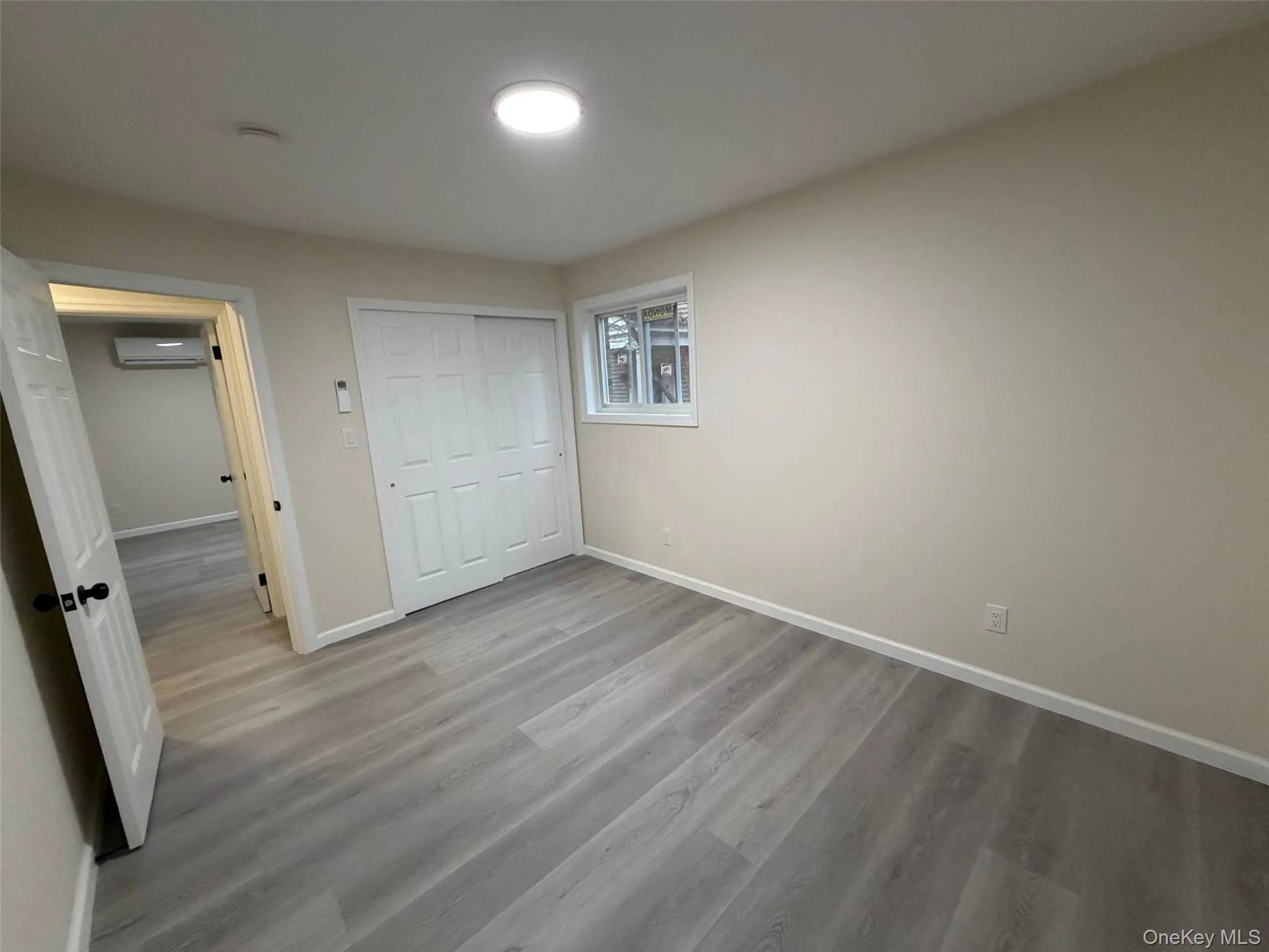 Unfurnished bedroom featuring light wood-style floors, a closet, and a wall mounted air conditioner Unfurnished bedroom featuring light wood-style floors, a closet, and a wall mounted air conditioner