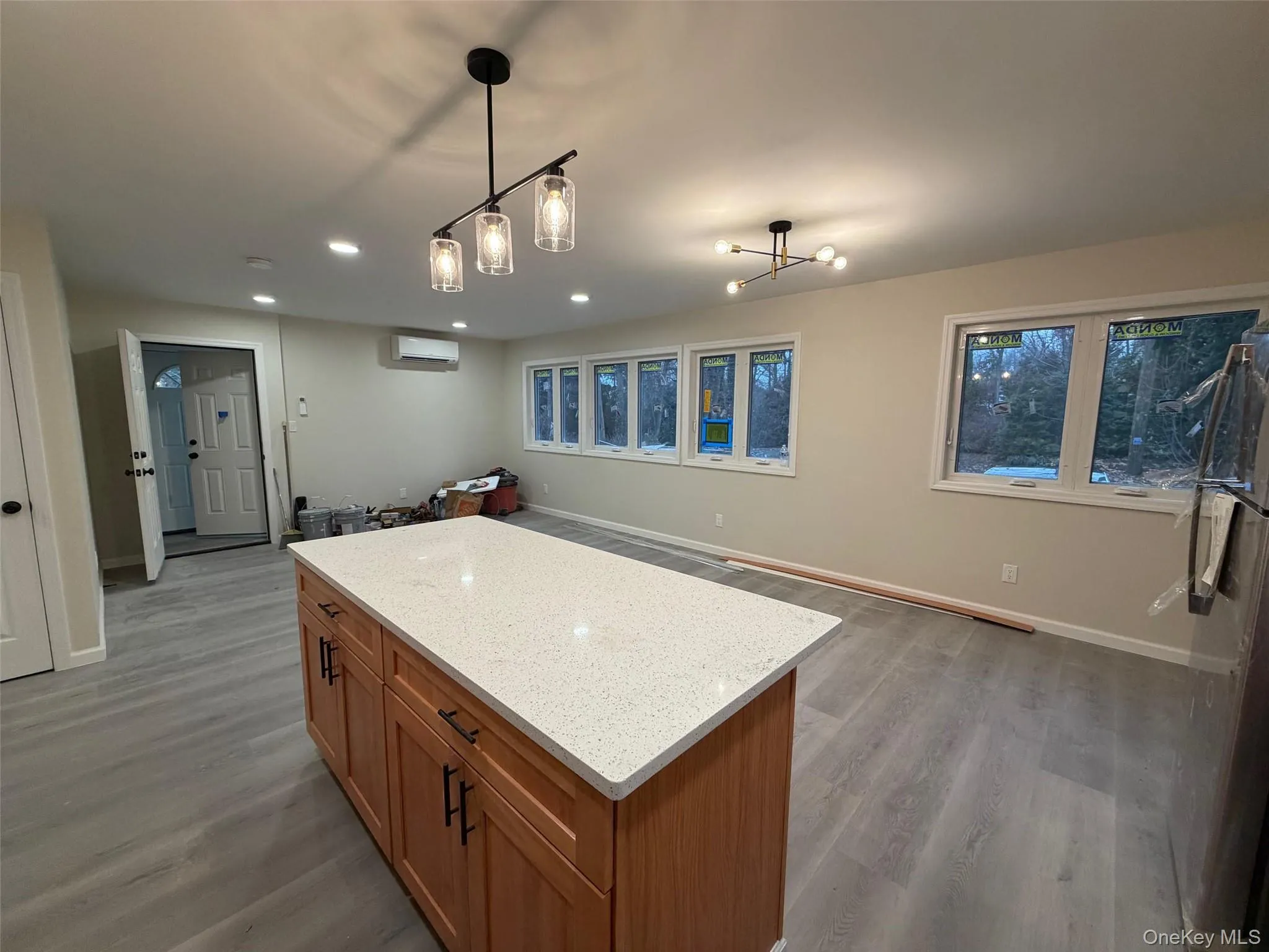 Kitchen featuring brown cabinets, light stone counters, open floor plan, fridge, and a kitchen island Kitchen featuring brown cabinets, light stone counters, open floor plan, fridge, and a kitchen island