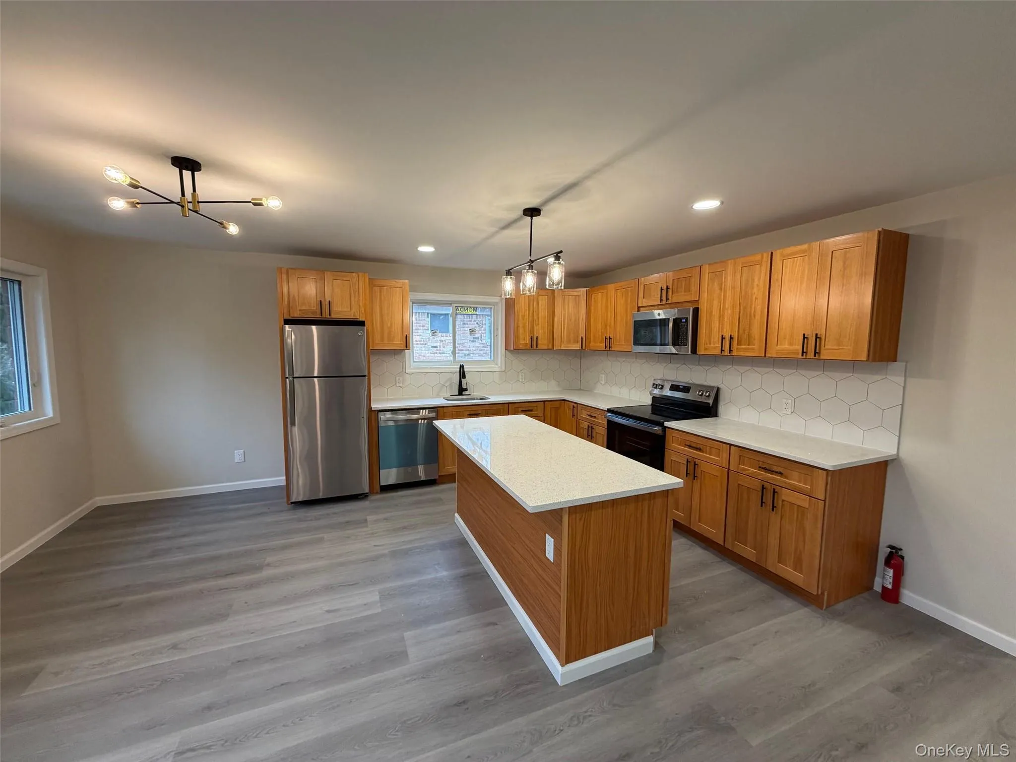 Kitchen with brown cabinets, a chandelier, stainless steel appliances, a kitchen island, and recessed lighting Kitchen with brown cabinets, a chandelier, stainless steel appliances, a kitchen island, and recessed lighting