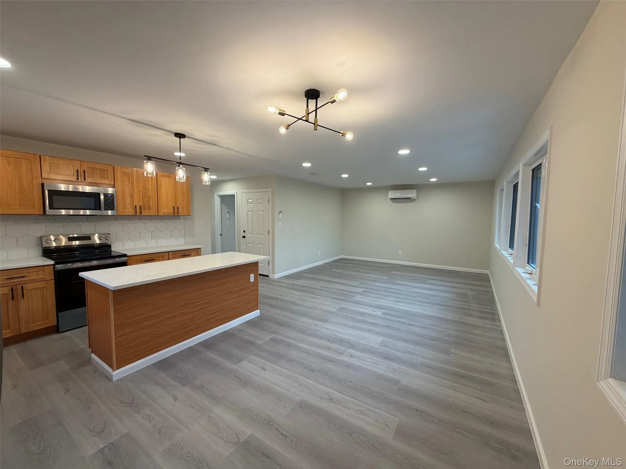 Kitchen with stainless steel appliances, recessed lighting, backsplash, a kitchen island, and light wood finished floors Kitchen with stainless steel appliances, recessed lighting, backsplash, a kitchen island, and light wood finished floors