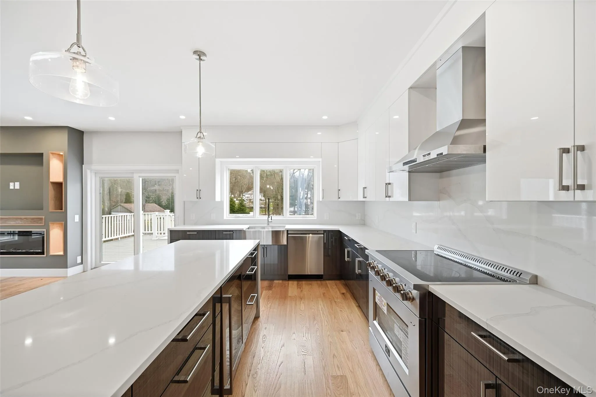 Kitchen featuring decorative light fixtures, appliances with stainless steel finishes, white cabinetry, light wood-style flooring, and light stone counters Kitchen featuring decorative light fixtures, appliances with stainless steel finishes, white cabinetry, light wood-style flooring, and light stone counters