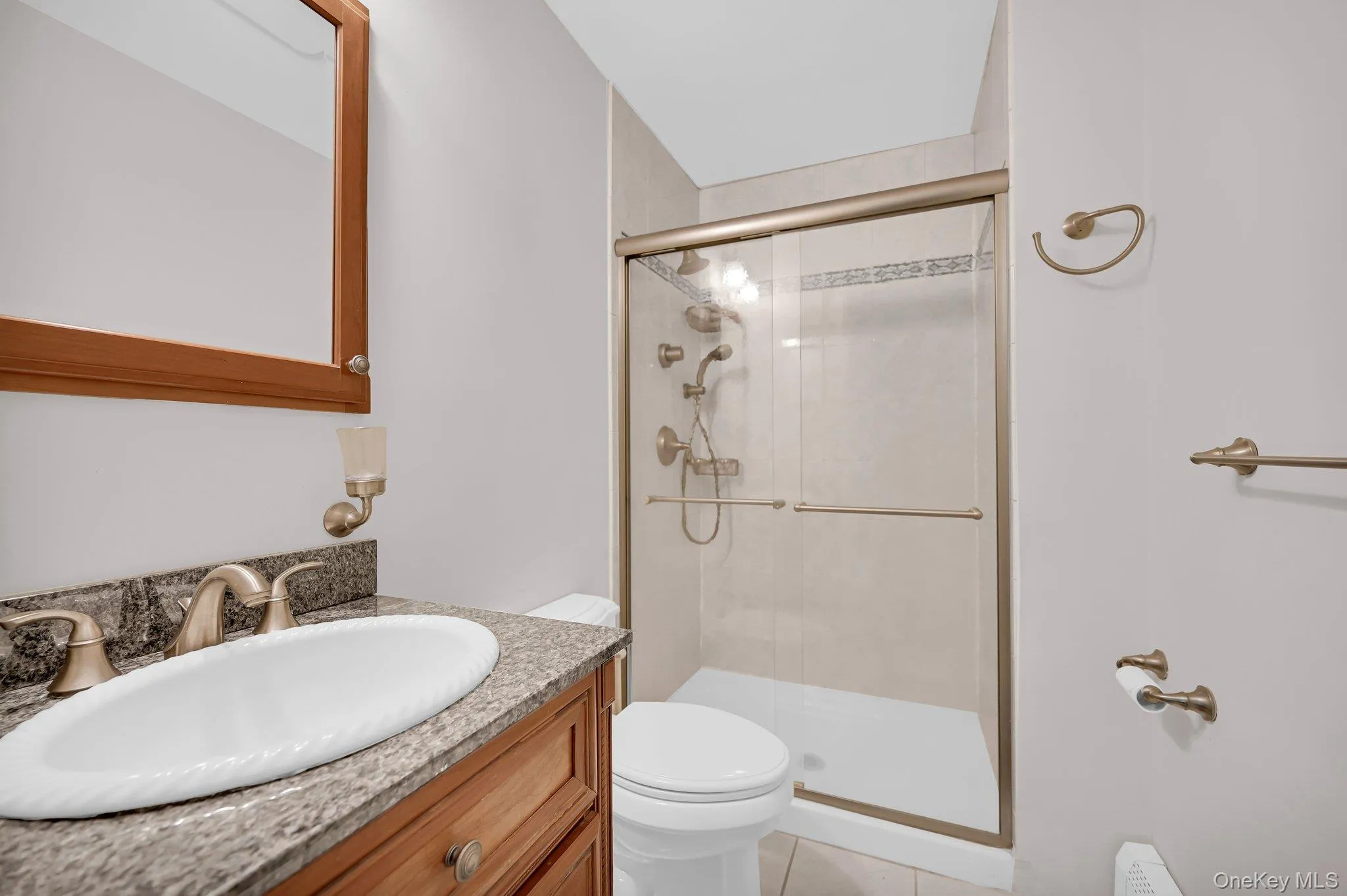 Full bath featuring vanity, a stall shower, and light tile patterned floors Full bath featuring vanity, a stall shower, and light tile patterned floors