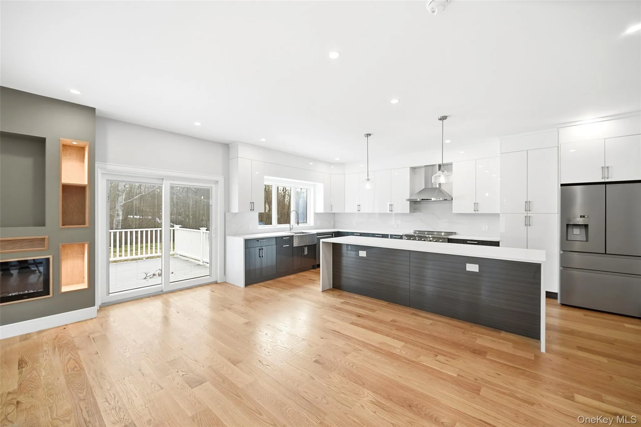 Kitchen featuring white cabinetry, modern cabinets, stainless steel fridge, a kitchen island, and recessed lighting Kitchen featuring white cabinetry, modern cabinets, stainless steel fridge, a kitchen island, and recessed lighting