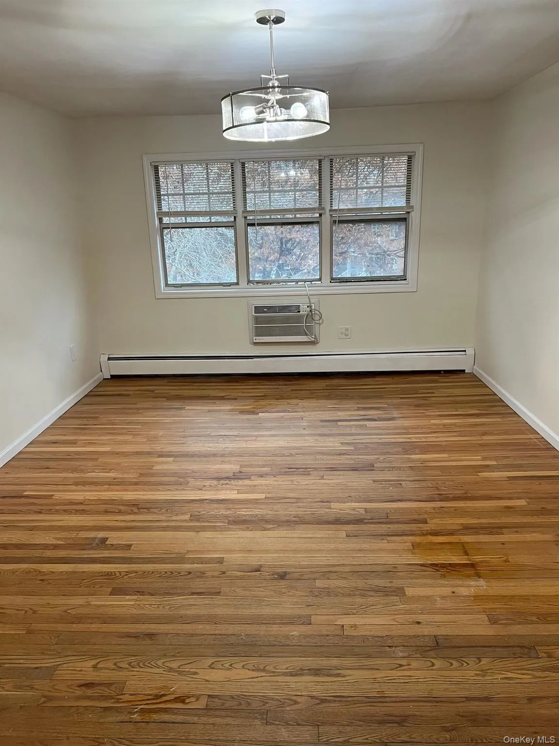 Spare room with Living room/Dining area hardwood flooring, plenty of natural light and chandelier Spare room with Living room/Dining area hardwood flooring, plenty of natural light and chandelier