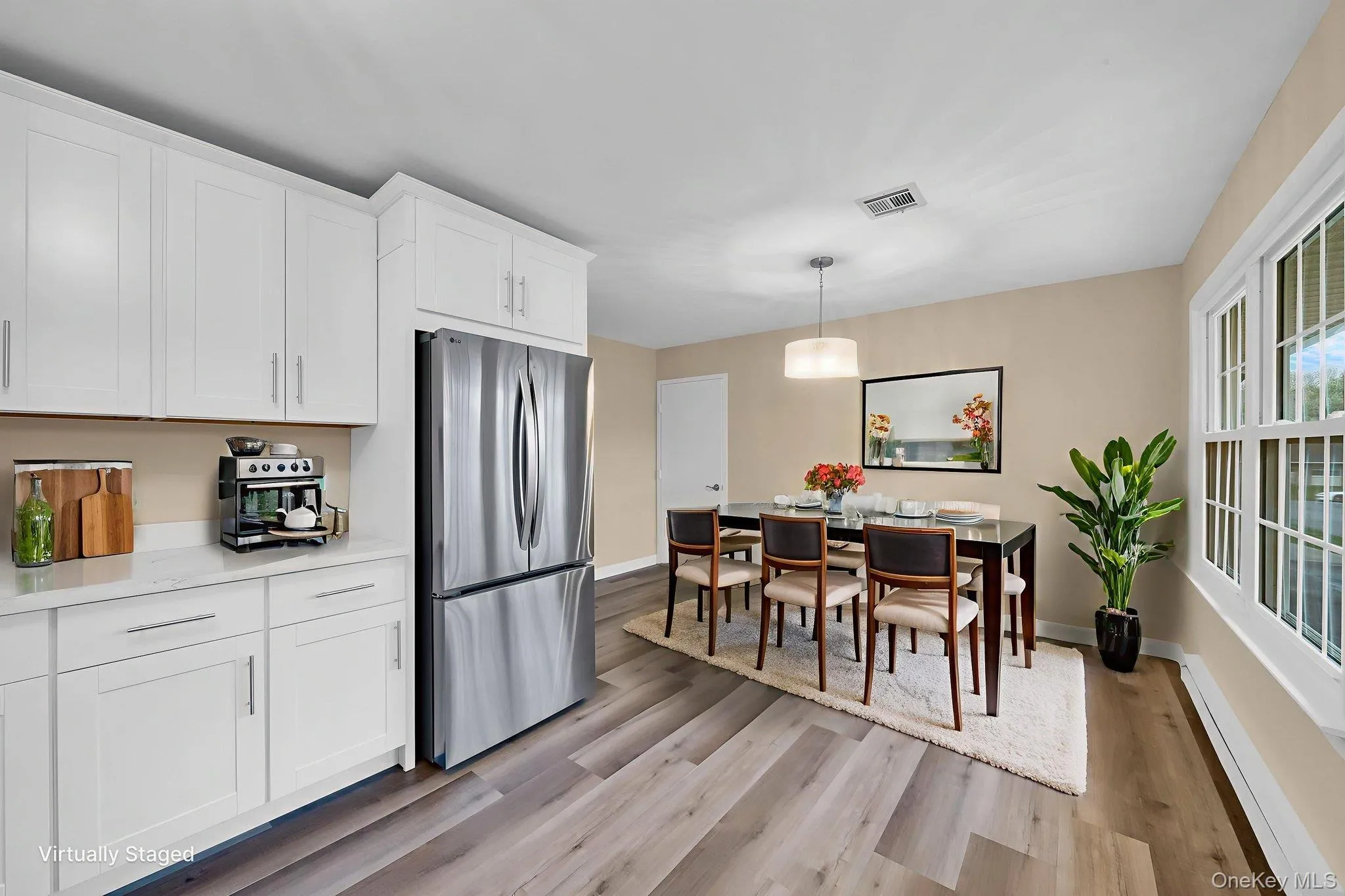 Kitchen with white cabinetry, freestanding refrigerator, a baseboard heating unit, and hanging light fixtures Kitchen with white cabinetry, freestanding refrigerator, a baseboard heating unit, and hanging light fixtures