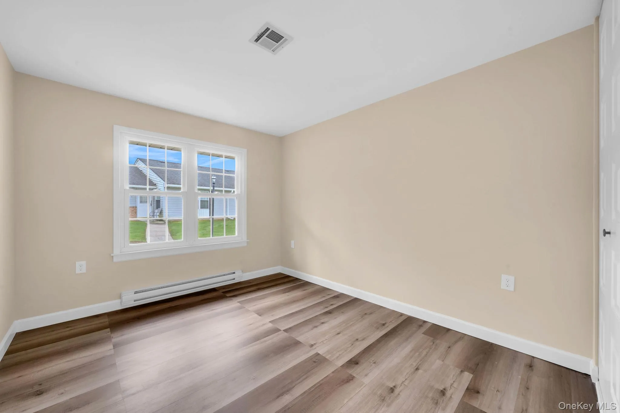 Spare room featuring a baseboard heating unit and light wood-style floors Spare room featuring a baseboard heating unit and light wood-style floors