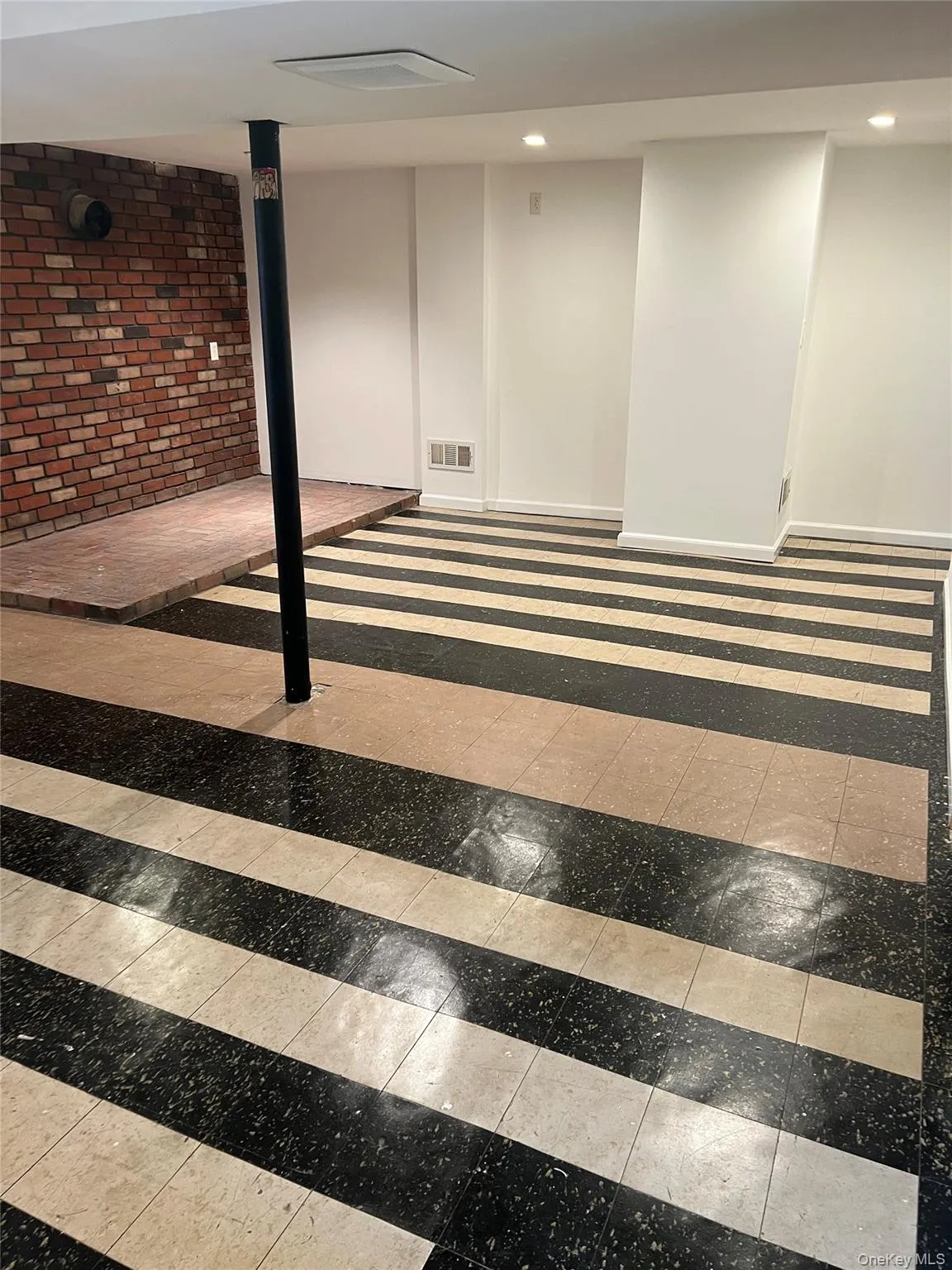 Finished below grade area featuring baseboards and brick wall Finished below grade area featuring baseboards and brick wall