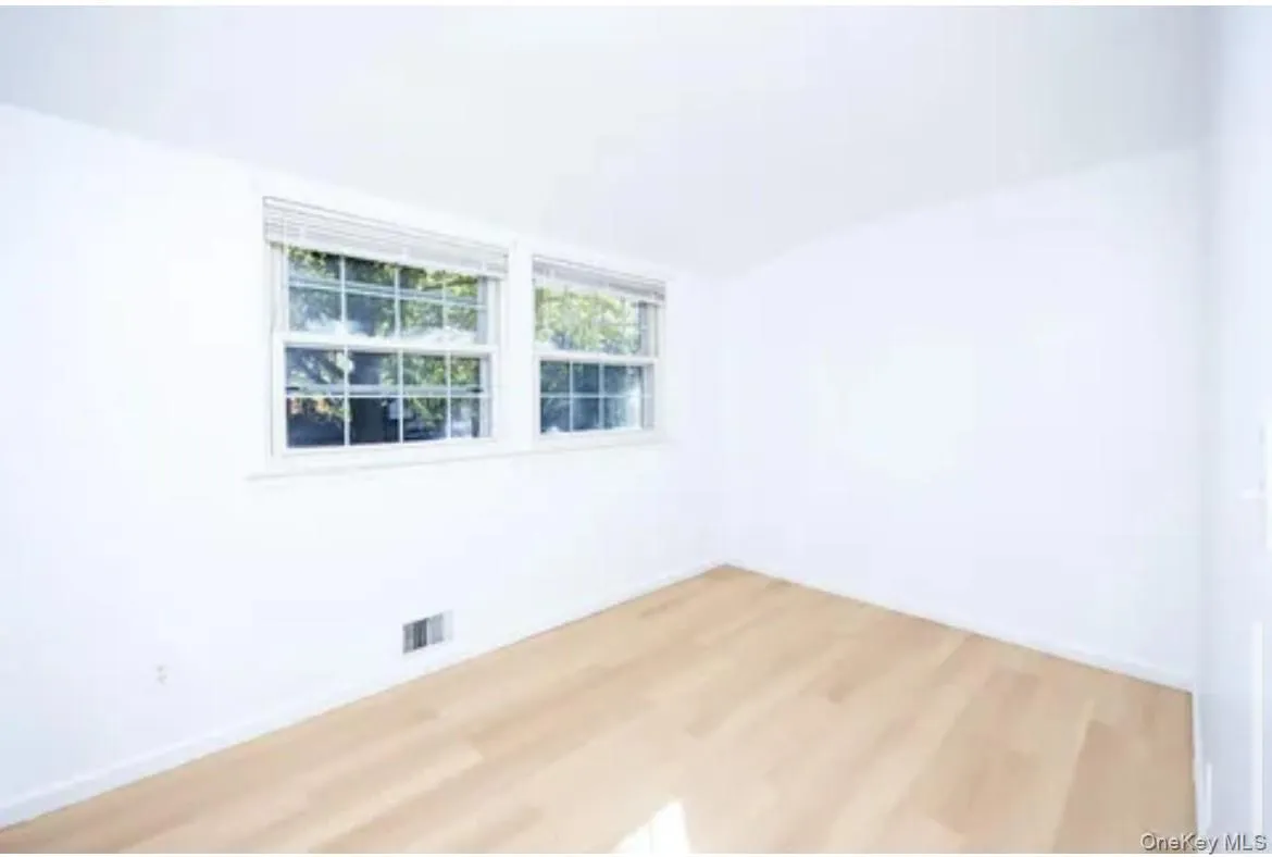 Unfurnished room featuring wood finished floors and vaulted ceiling Unfurnished room featuring wood finished floors and vaulted ceiling
