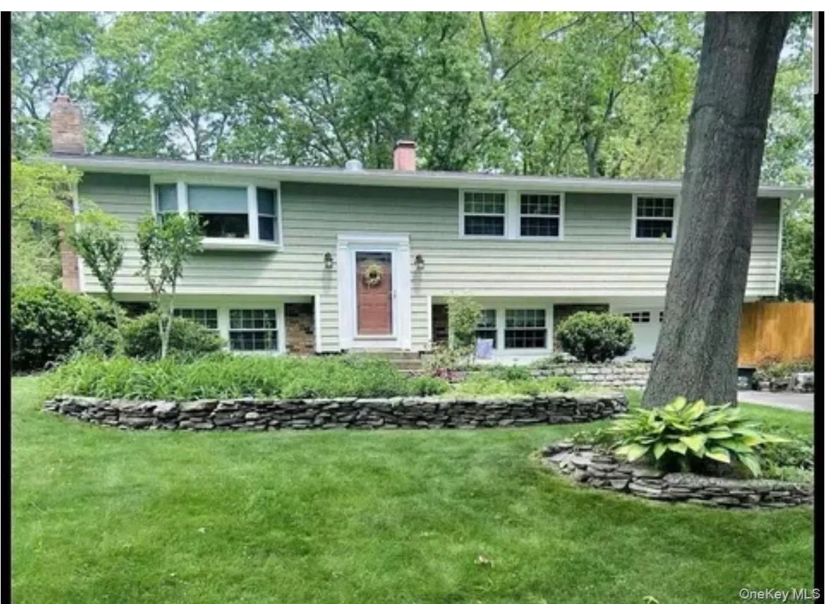 Split foyer home featuring a chimney, a front lawn, and a garage Split foyer home featuring a chimney, a front lawn, and a garage