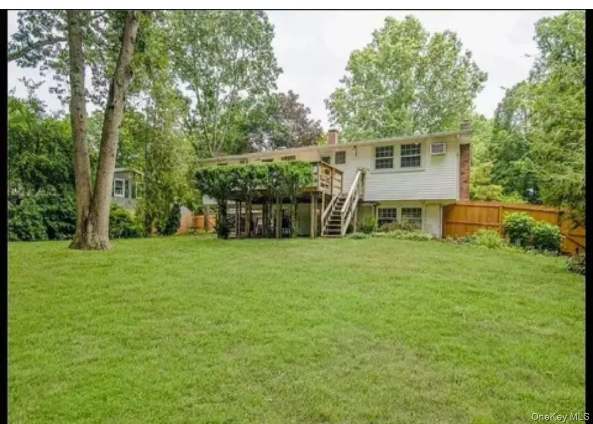View of yard featuring stairway, a deck, and view of wooded area View of yard featuring stairway, a deck, and view of wooded area