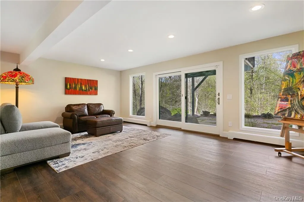 Living room with recessed lighting, dark wood-style floors, beamed ceiling, and a baseboard heating unit Living room with recessed lighting, dark wood-style floors, beamed ceiling, and a baseboard heating unit