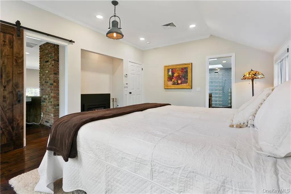 Bedroom with ensuite bath, a barn door, multiple windows, hardwood / wood-style flooring, and recessed lighting Bedroom with ensuite bath, a barn door, multiple windows, hardwood / wood-style flooring, and recessed lighting