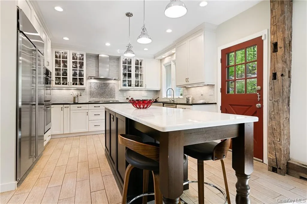 Kitchen featuring hanging light fixtures, white cabinetry, appliances with stainless steel finishes, a kitchen island, and recessed lighting Kitchen featuring hanging light fixtures, white cabinetry, appliances with stainless steel finishes, a kitchen island, and recessed lighting