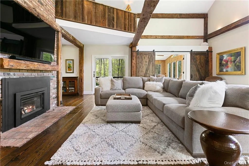 Living room with dark wood-type flooring, a fireplace, and a barn door Living room with dark wood-type flooring, a fireplace, and a barn door