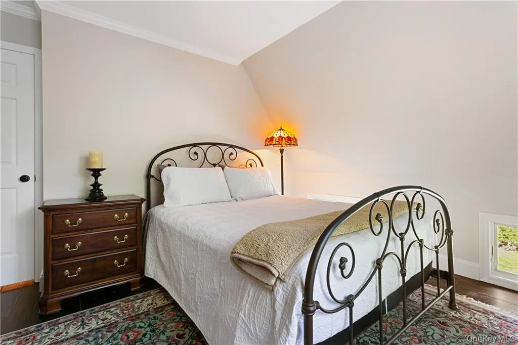 Bedroom featuring ornamental molding, vaulted ceiling, and dark wood-style floors Bedroom featuring ornamental molding, vaulted ceiling, and dark wood-style floors