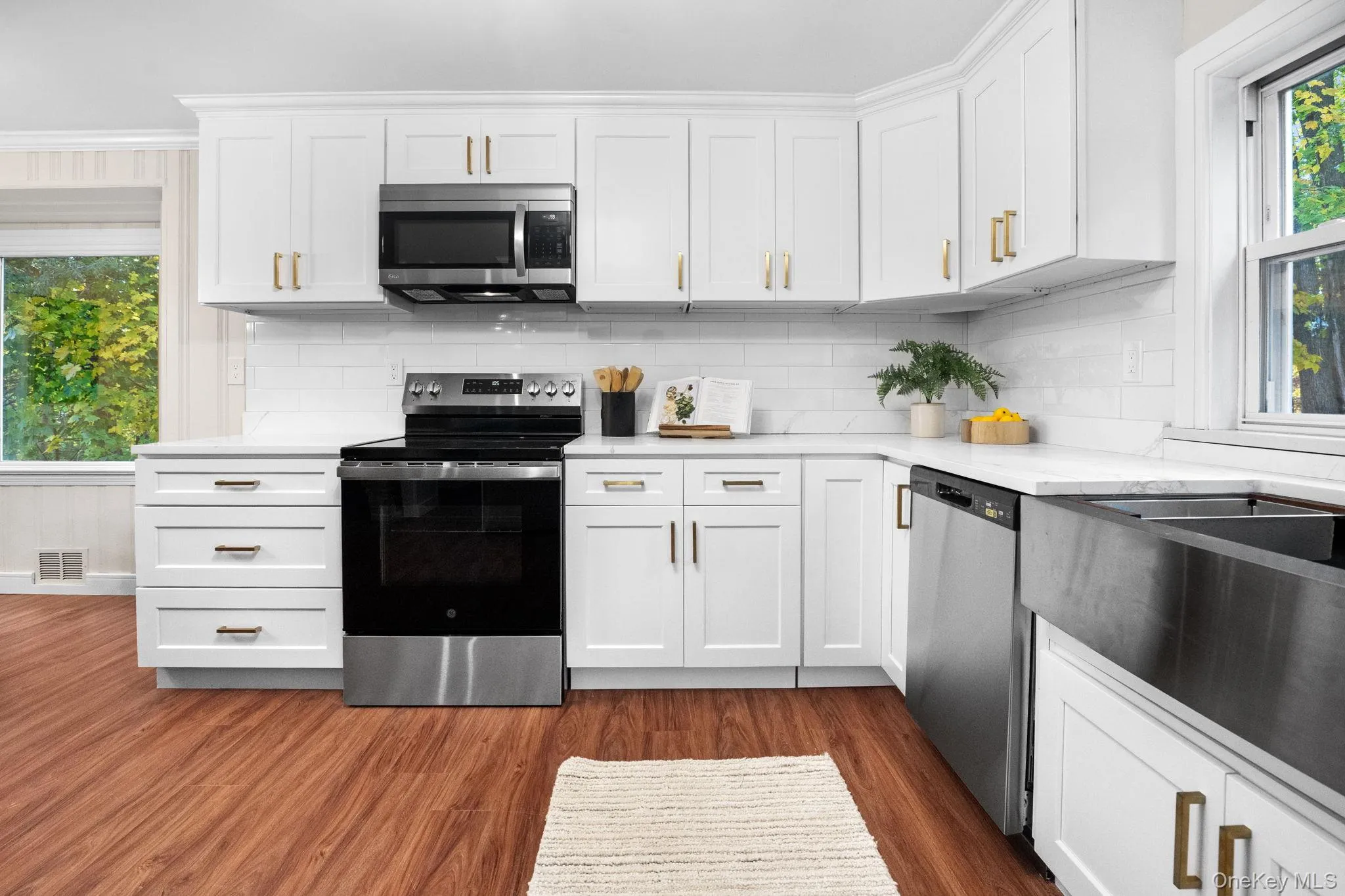 Newly renovated kitchen featuring stainless steel appliances, quartz countertops, and elegant white shaker cabinetry accented with brushed gold hardware. Newly renovated kitchen featuring stainless steel appliances, quartz countertops, and elegant white shaker cabinetry accented with brushed gold hardware.