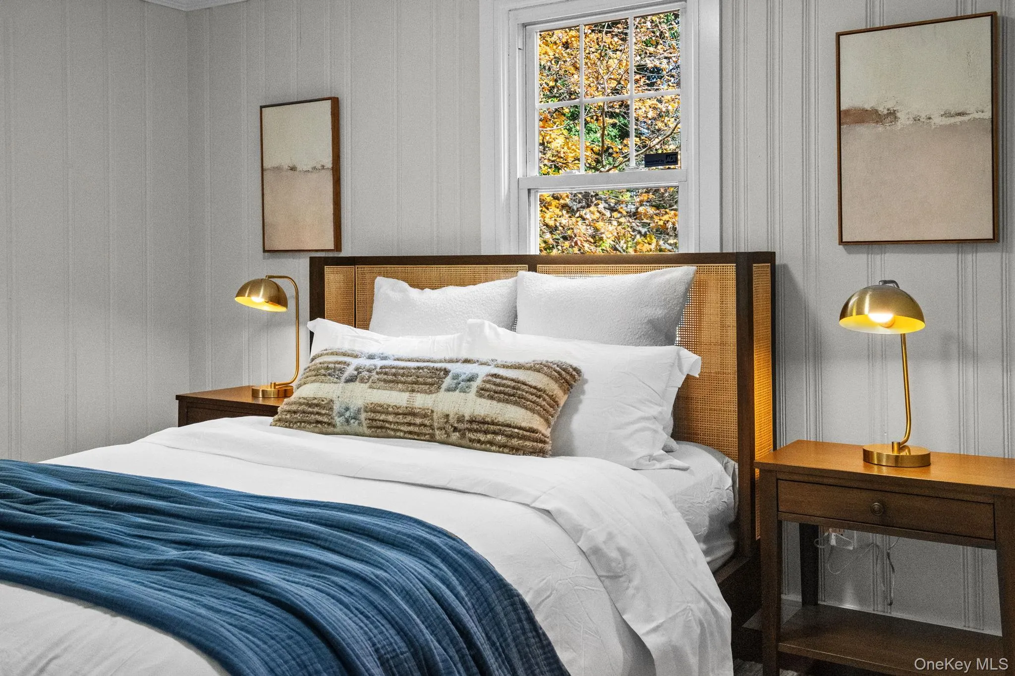 Warm and inviting bedroom accented by custom wall paneling, updated lighting, and peaceful treetop views. Warm and inviting bedroom accented by custom wall paneling, updated lighting, and peaceful treetop views.