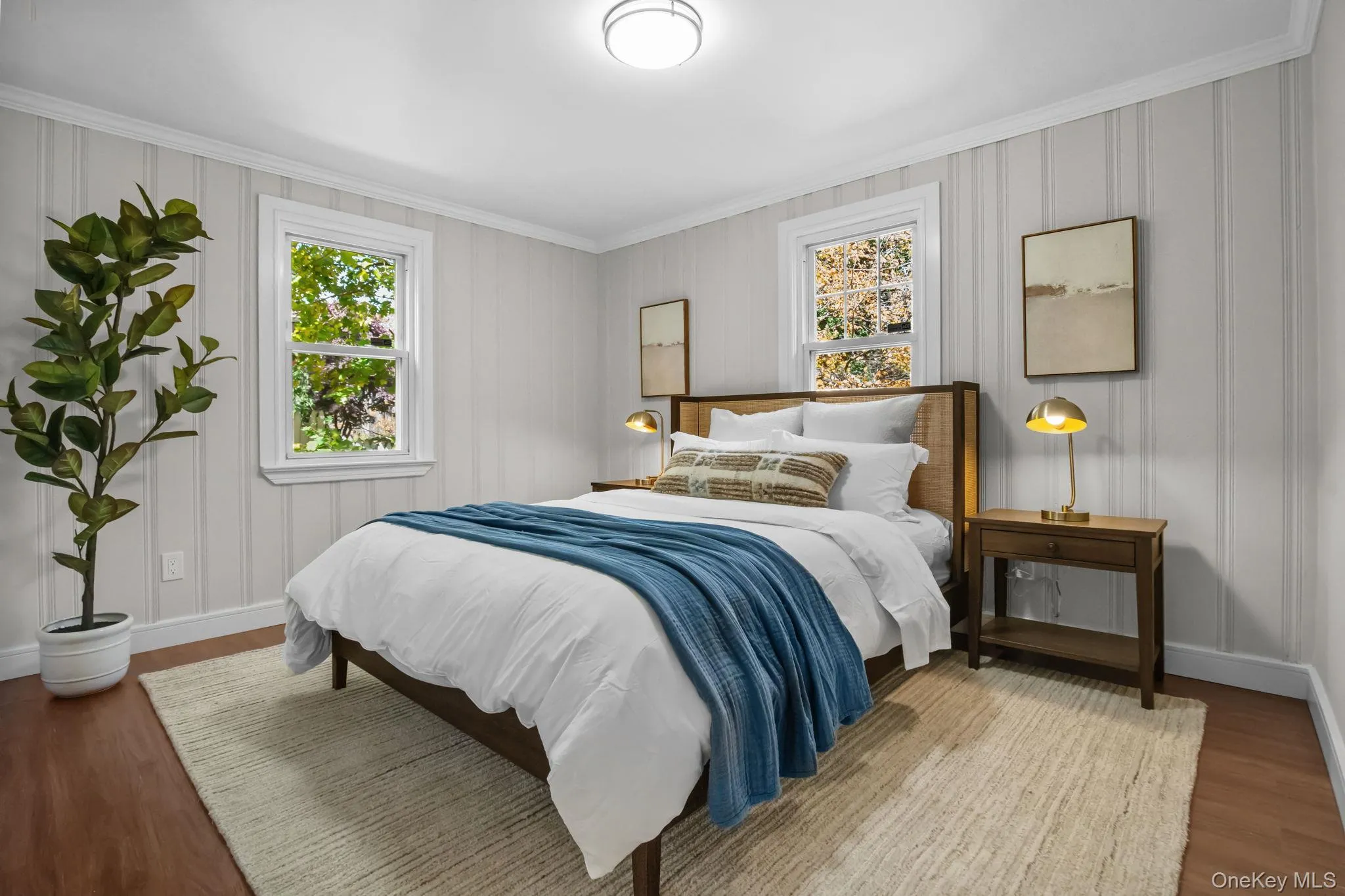 Bright secondary bedroom with hardwood floors, crown molding, and double windows overlooking the landscaped yard. Bright secondary bedroom with hardwood floors, crown molding, and double windows overlooking the landscaped yard.