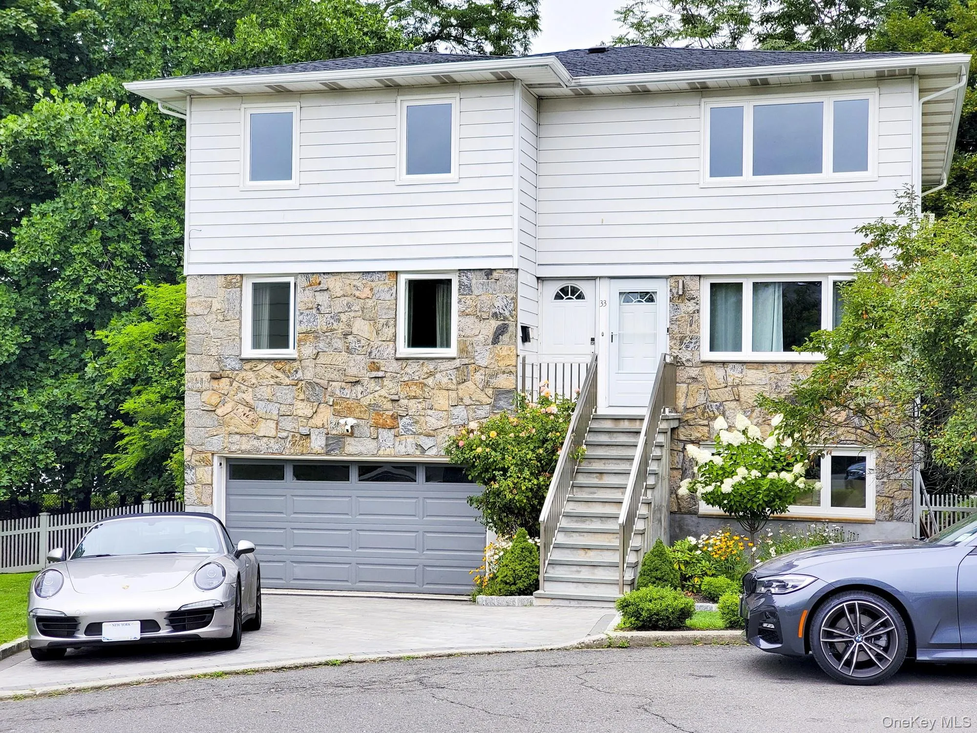 View of front of home featuring stone siding, a shingled roof, driveway, and an attached garage View of front of home featuring stone siding, a shingled roof, driveway, and an attached garage